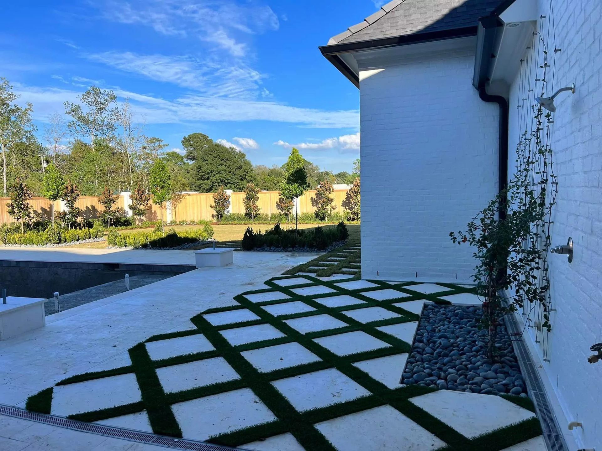 A white house with a patio and a swimming pool in the background.