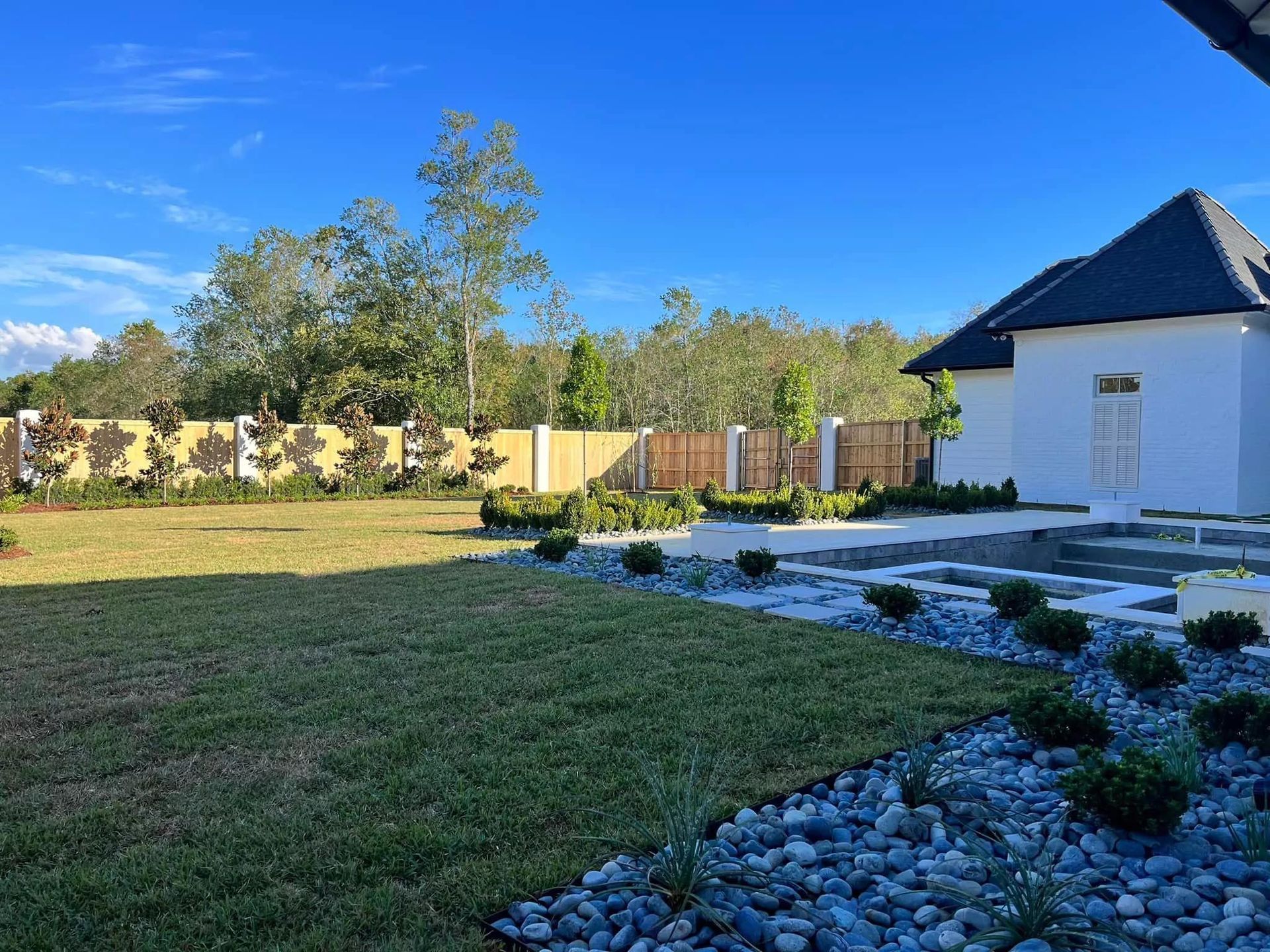A white house is sitting in the middle of a lush green field.