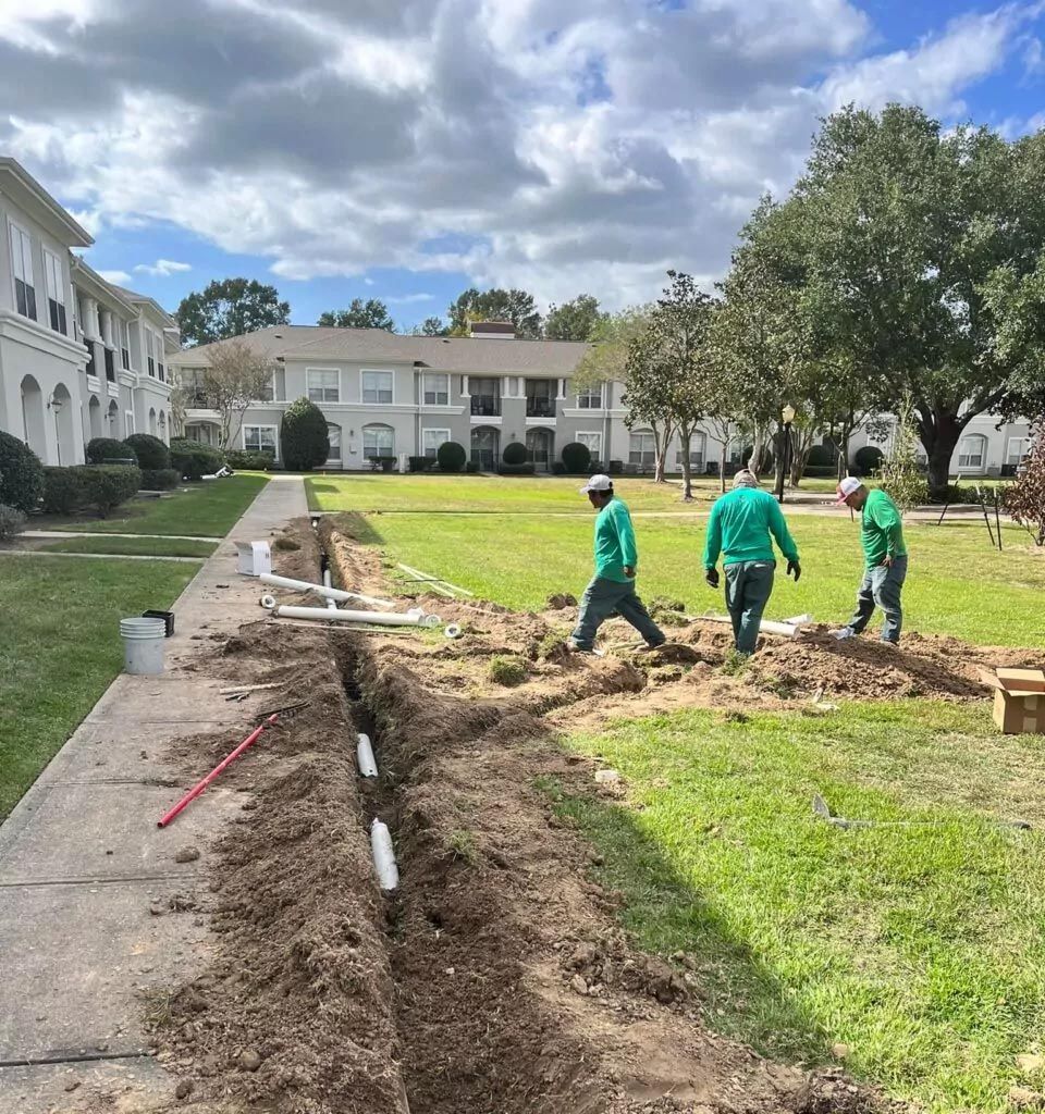 A group of men are working on a drainage system in a park.