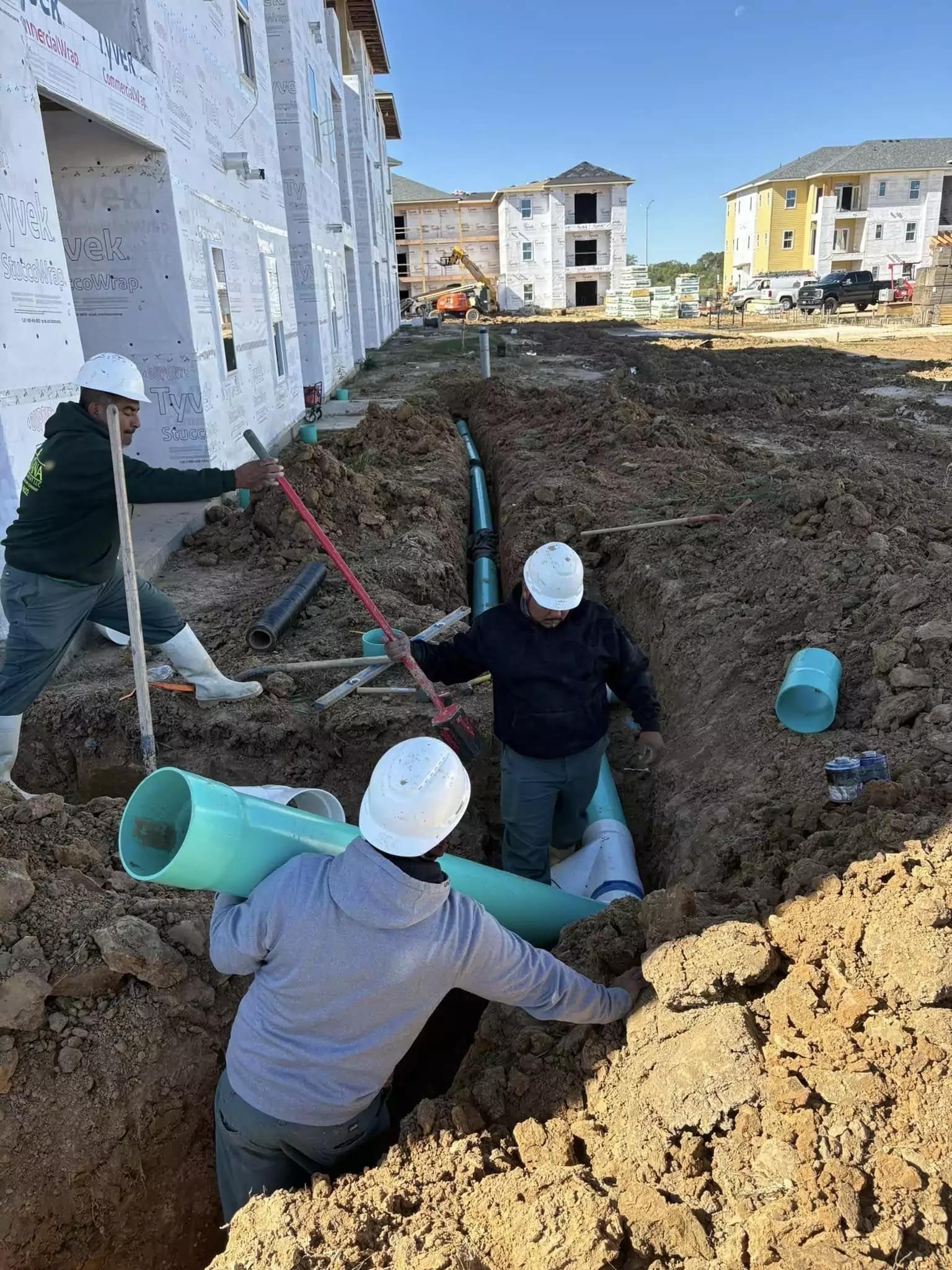 A group of construction workers are working on a pipe in the dirt.