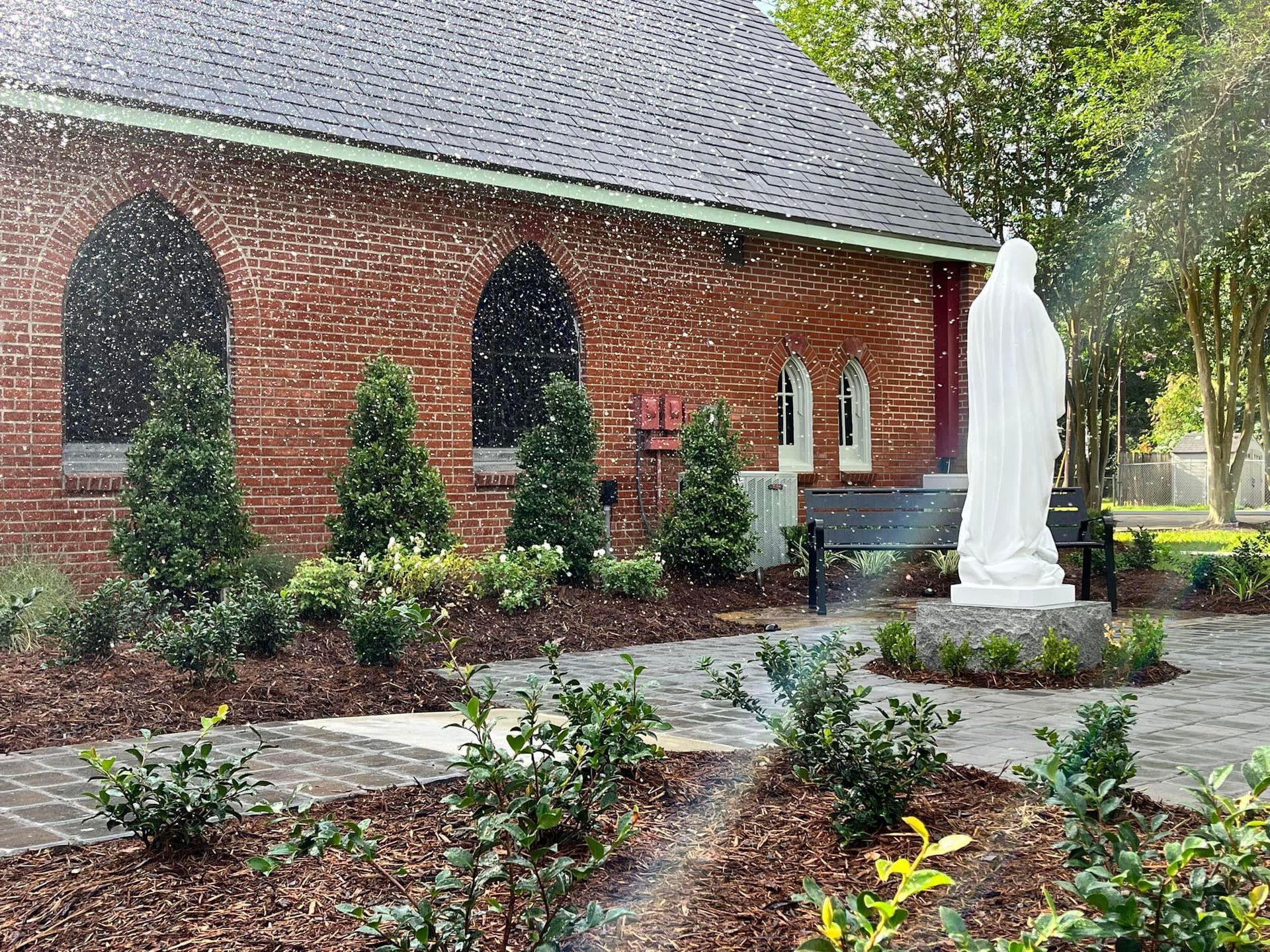 There is a statue of jesus in front of a brick church.