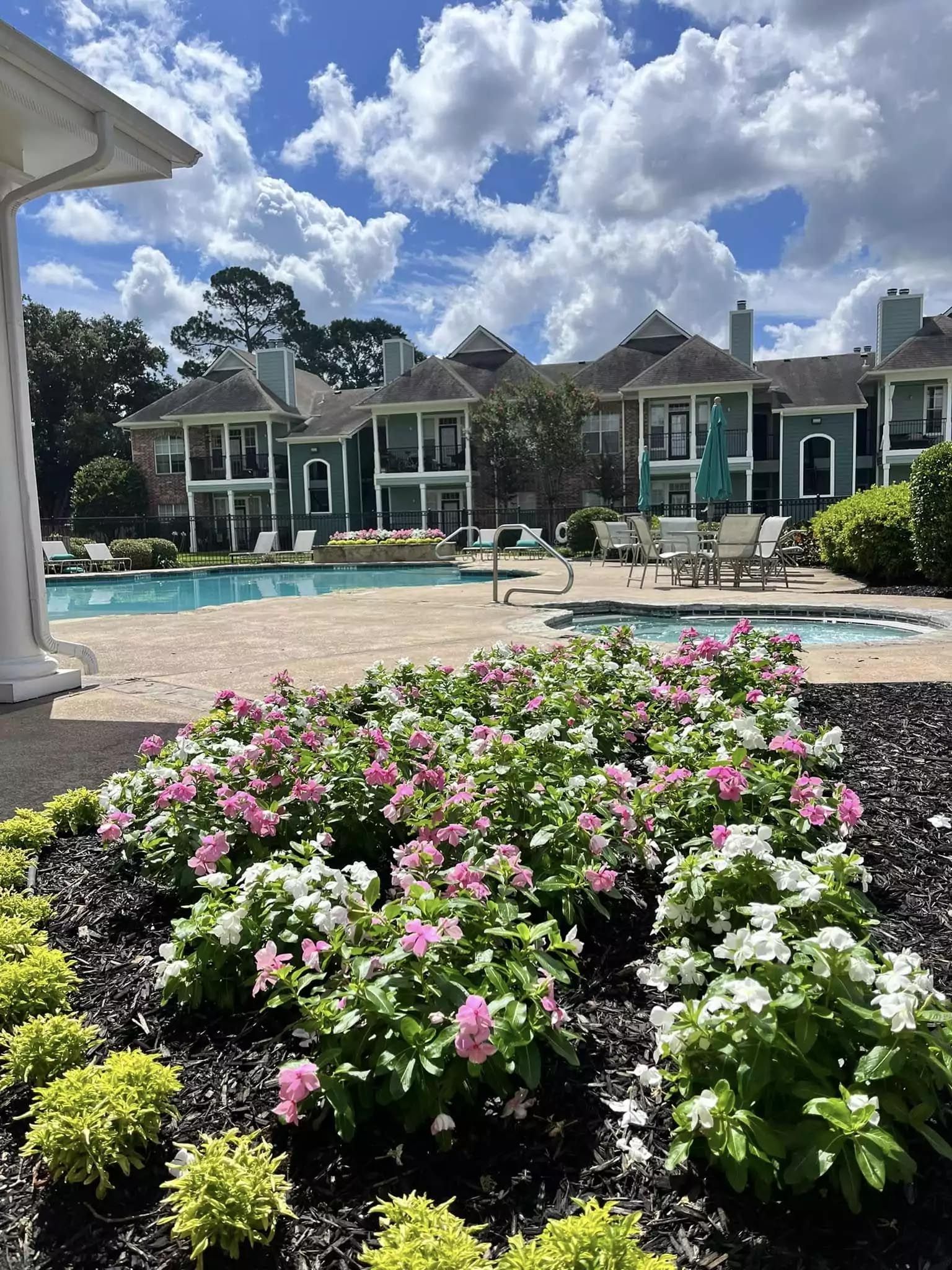 A swimming pool with a bunch of flowers in front of a building.