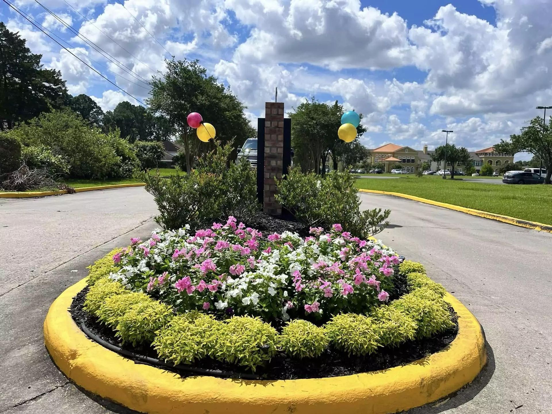 A circle of flowers and balloons on the side of the road