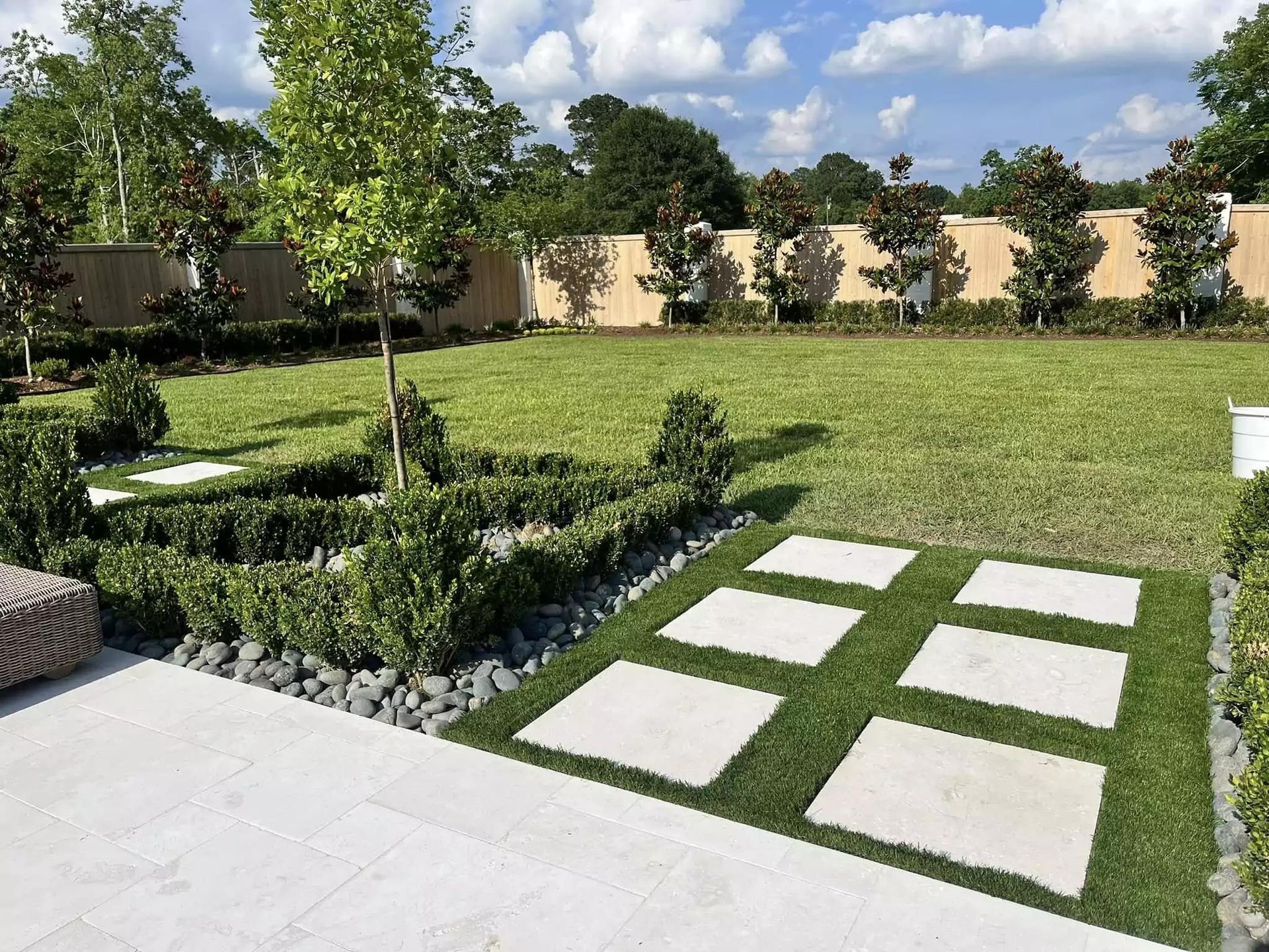 A lush green lawn with a concrete walkway leading to it.