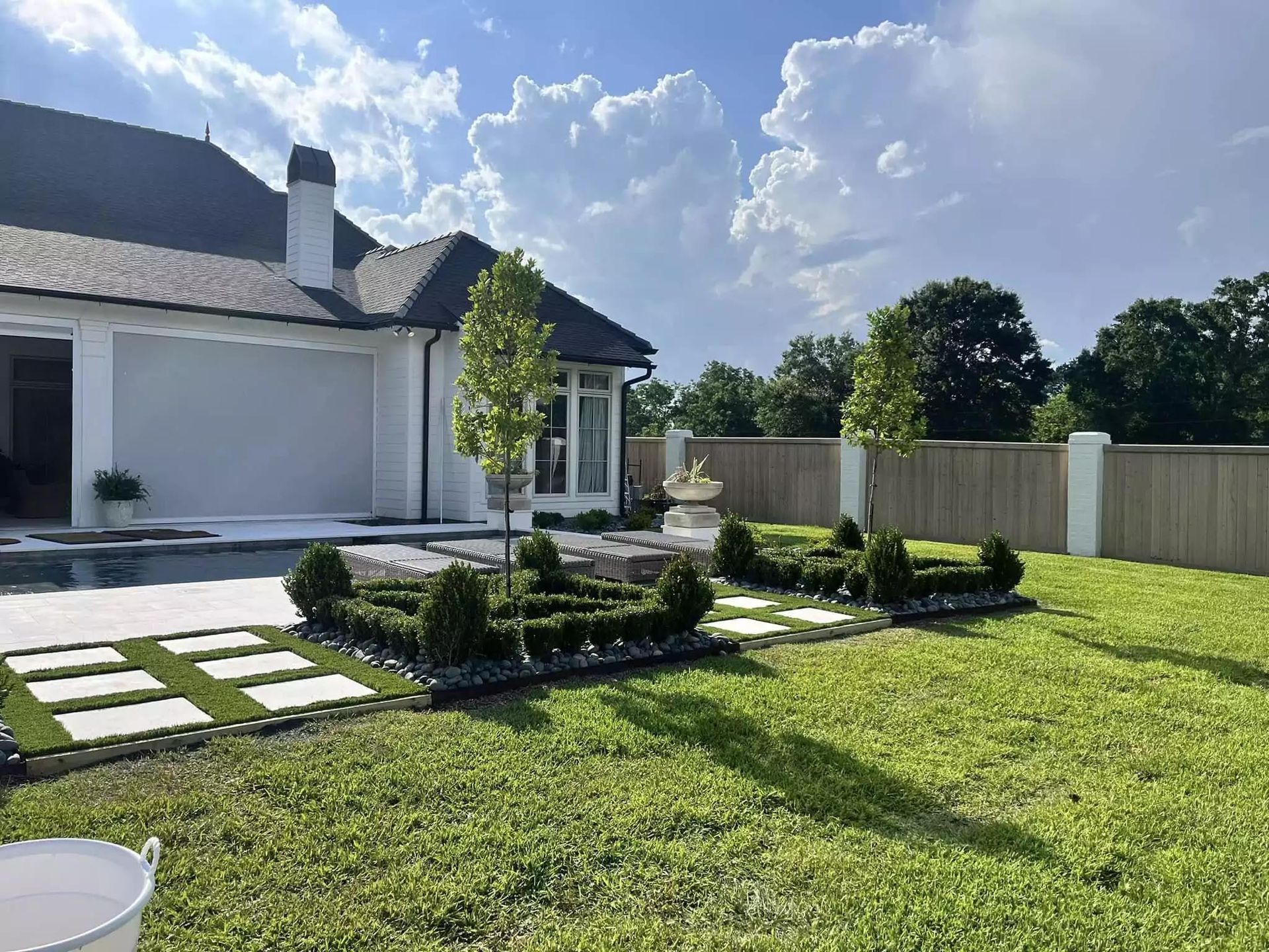 The backyard of a house with a large lawn and a pool.