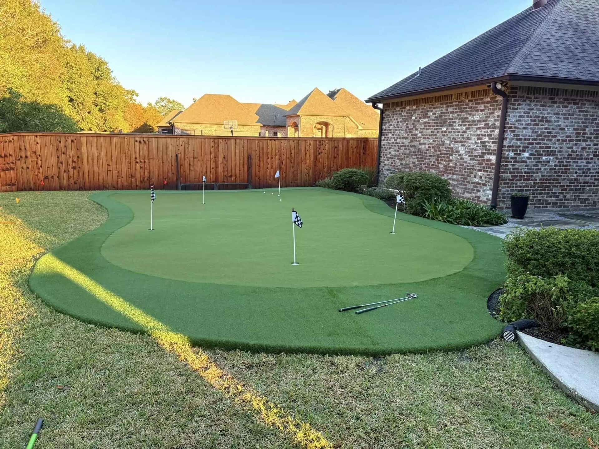 There is a putting green in the backyard of a house.