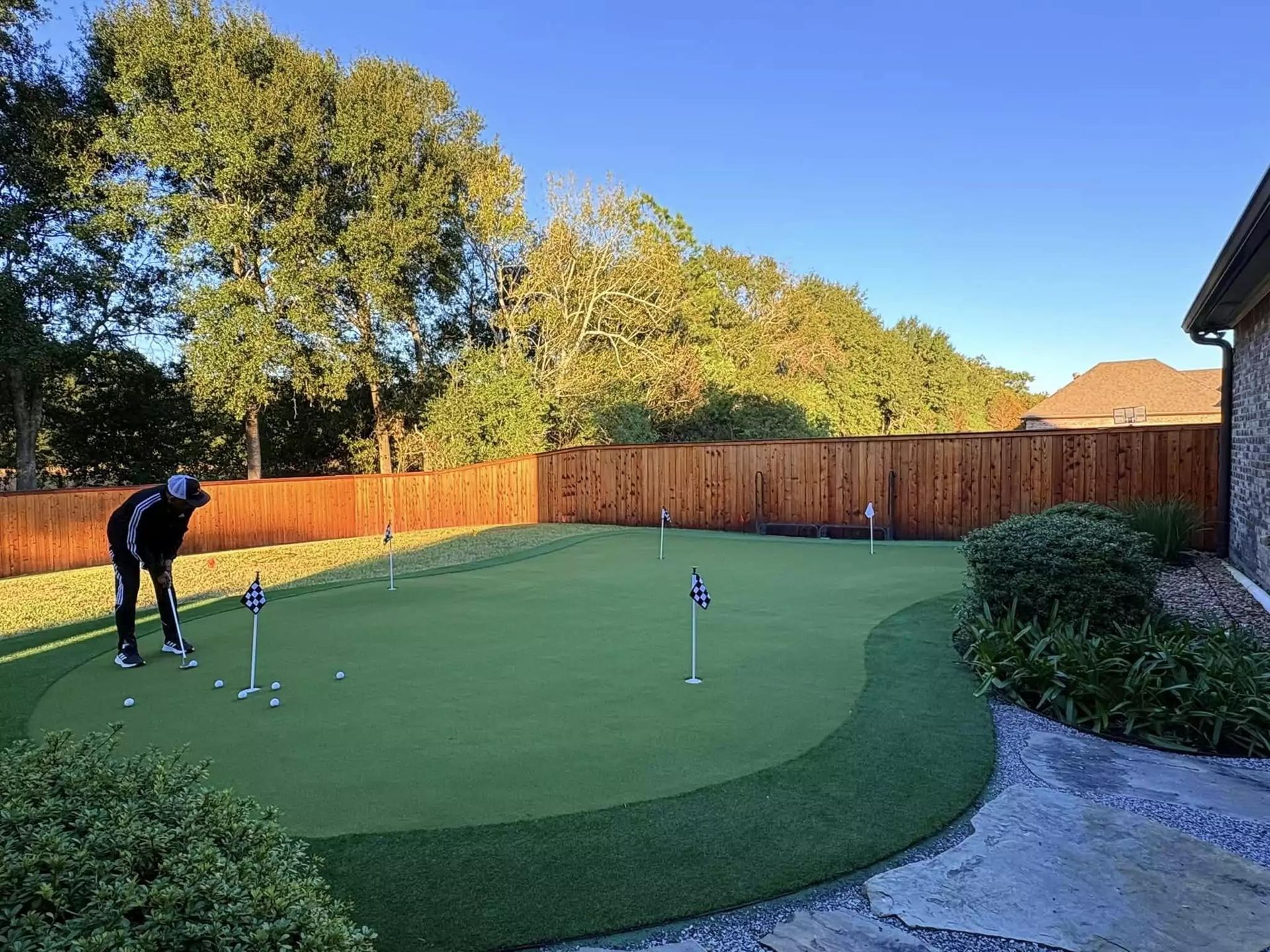 A man is putting a golf ball on a green in a backyard.
