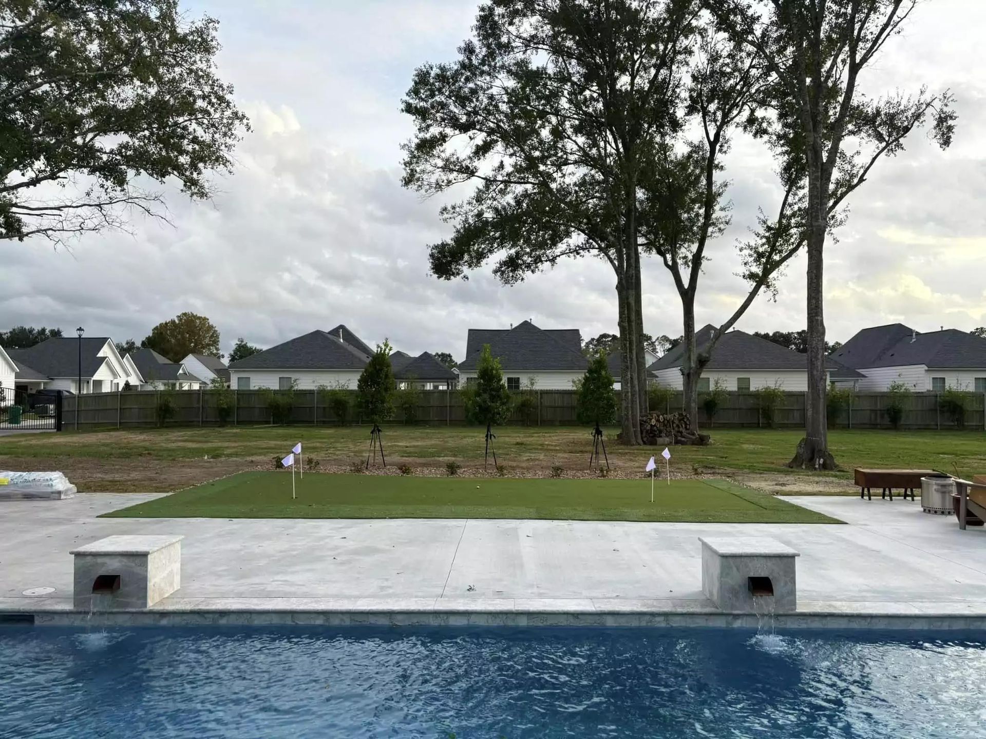 A swimming pool with a putting green in the background
