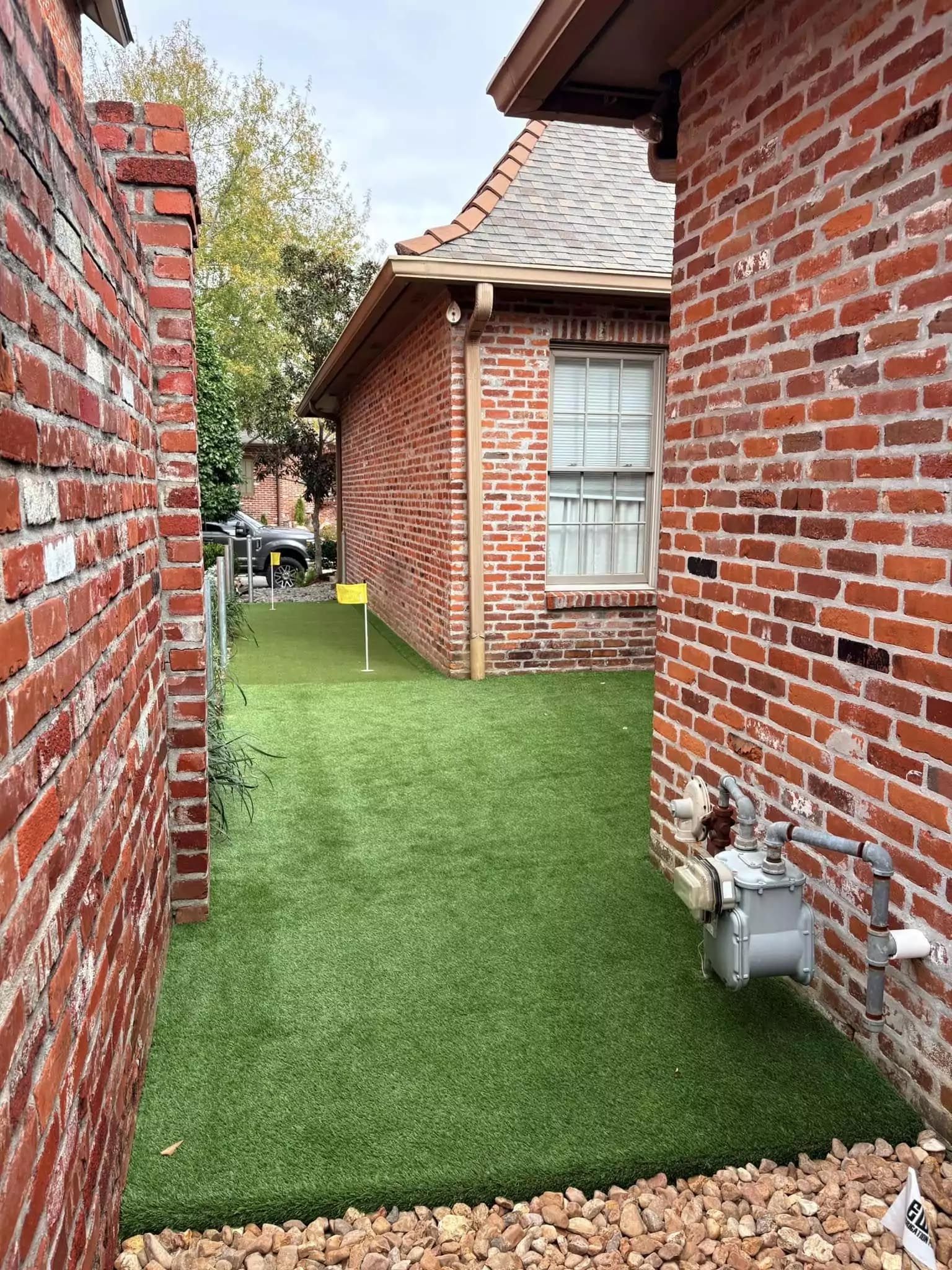There is a grassy area between two brick buildings.