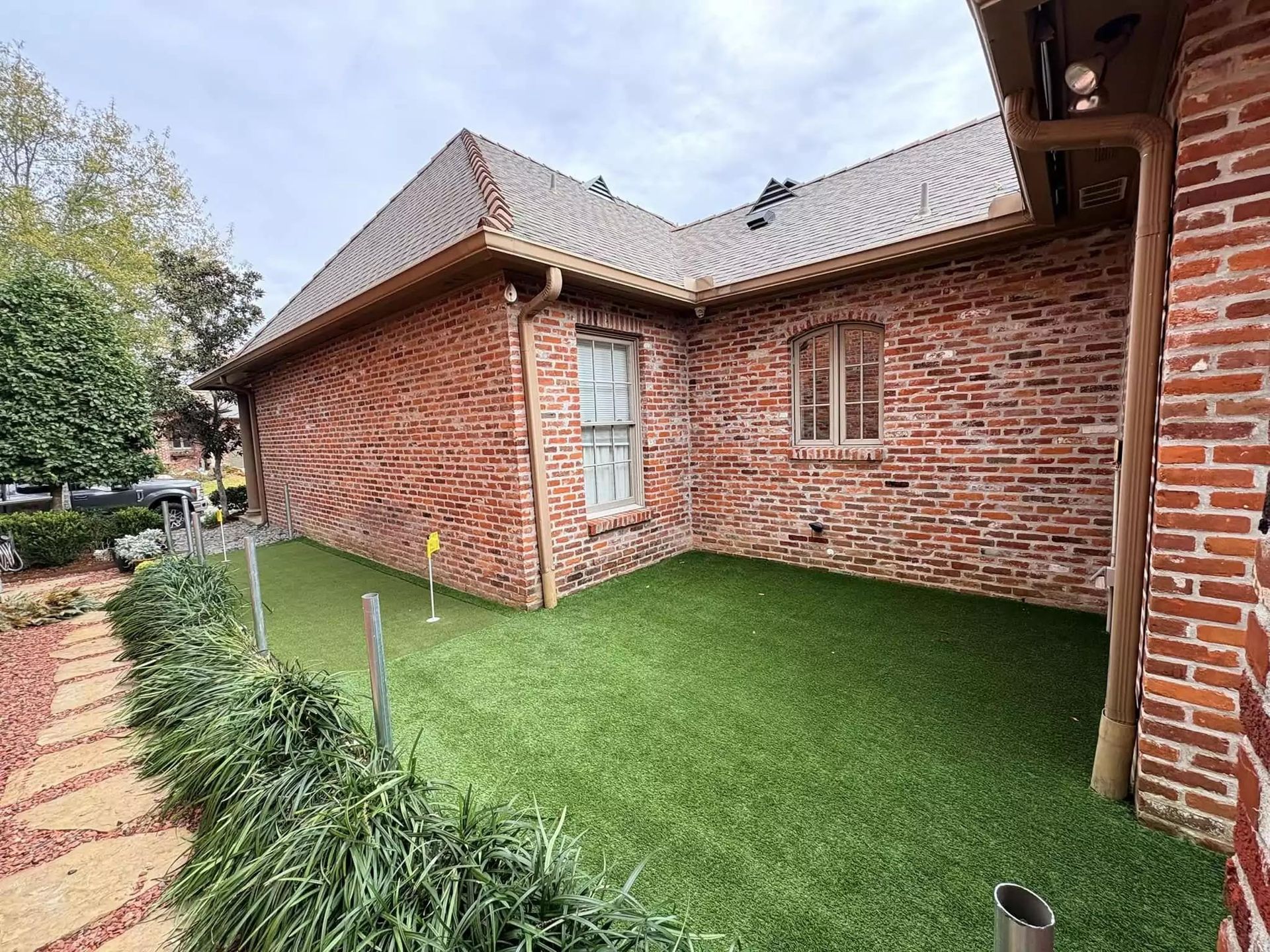 A brick house with a putting green in front of it.