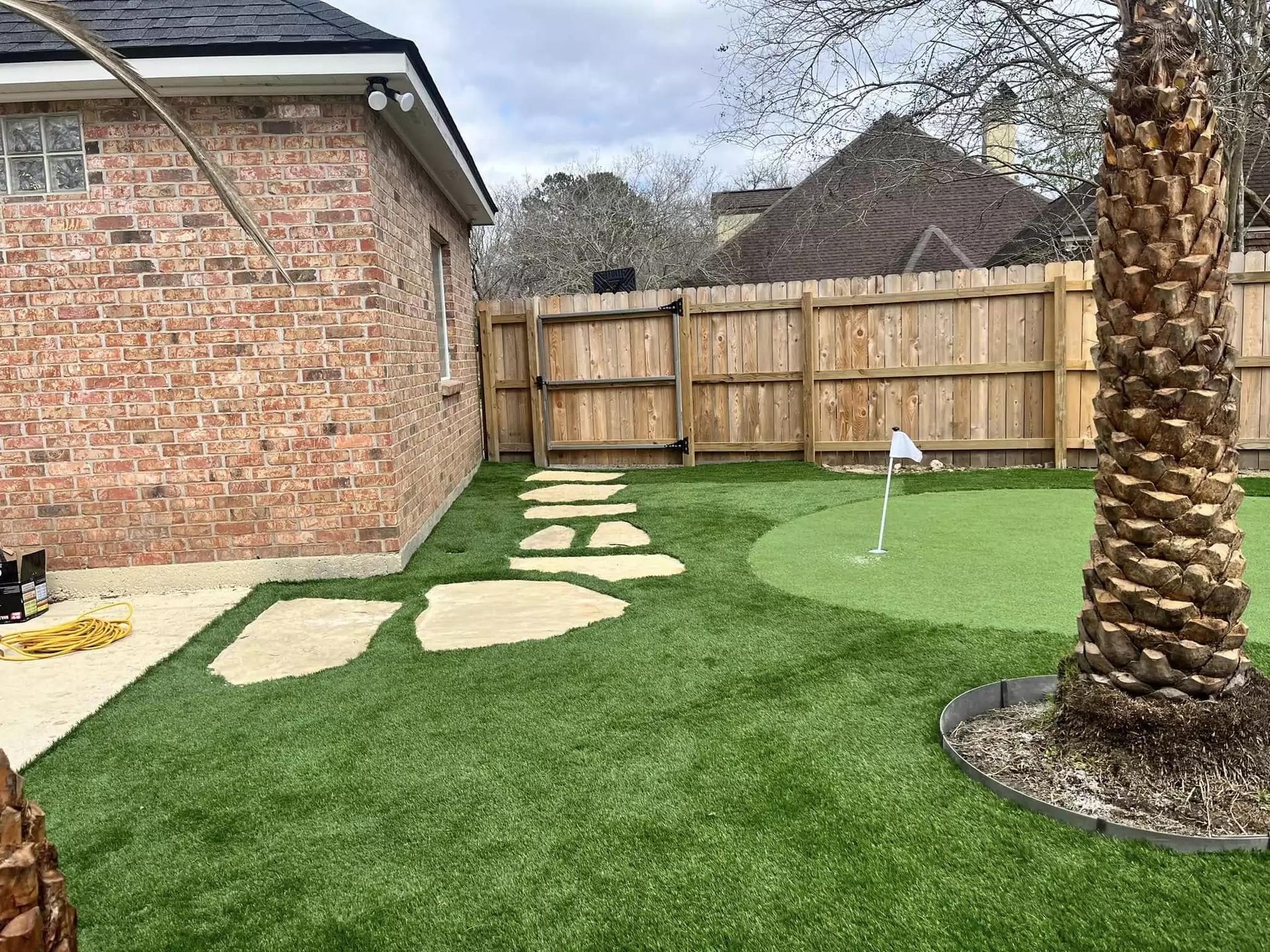 There is a putting green in the backyard of a house.