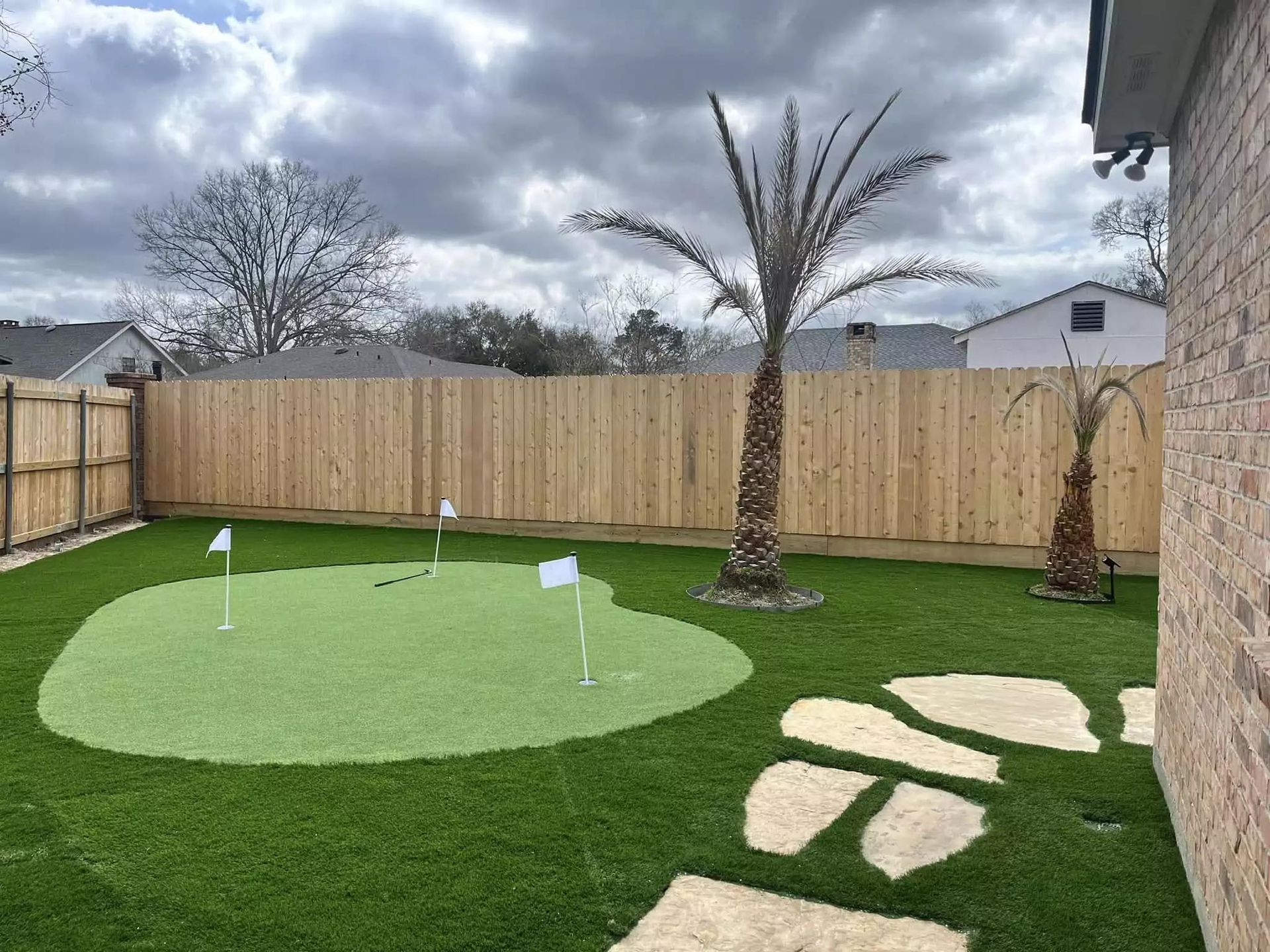 A backyard with a putting green and palm trees.