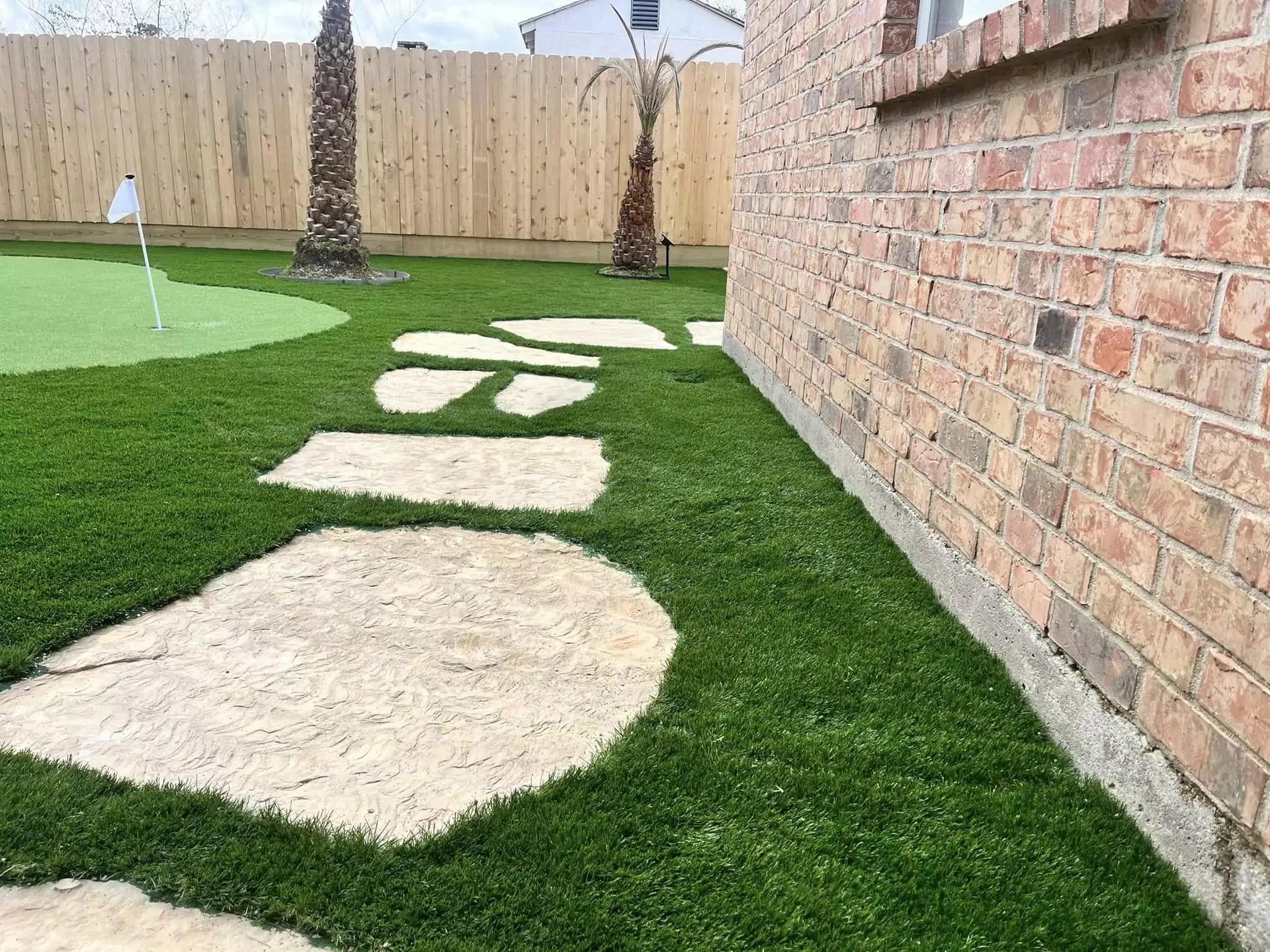 There is a putting green in the backyard of a house.