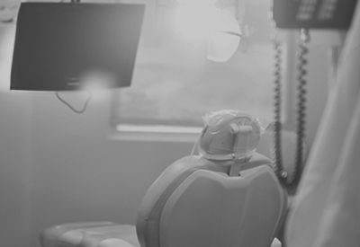 A black and white photo of a dental chair in a dental office.