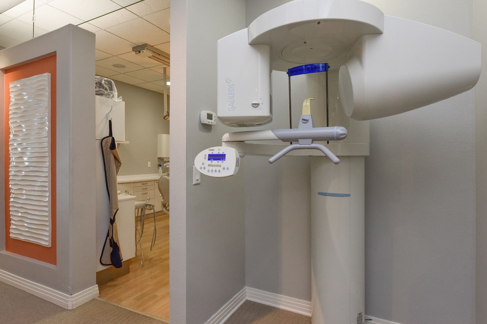 A dental office with a x-ray machine in the middle of the room.