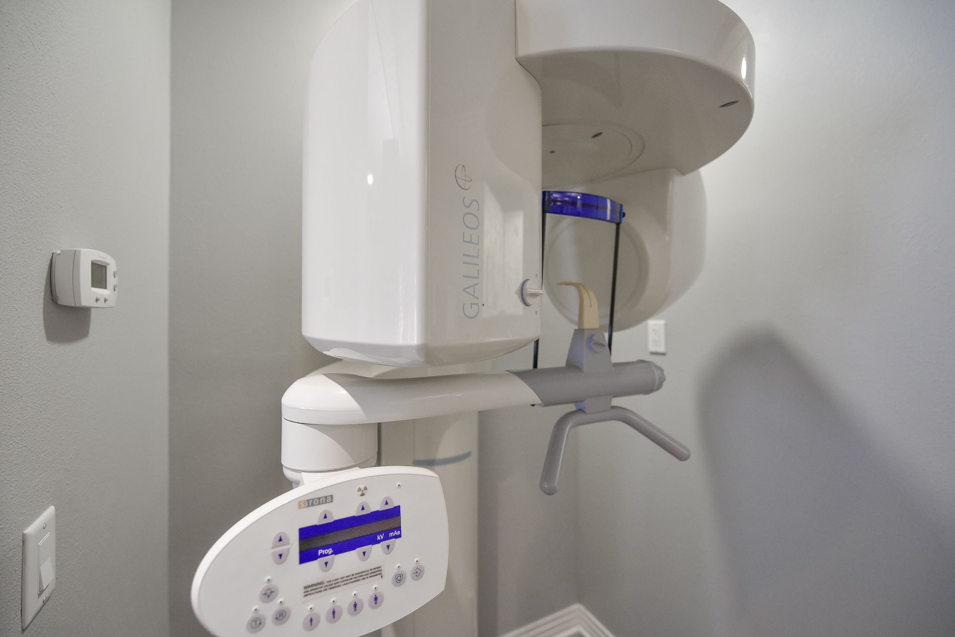 A dental x-ray machine is sitting in a room next to a wall.