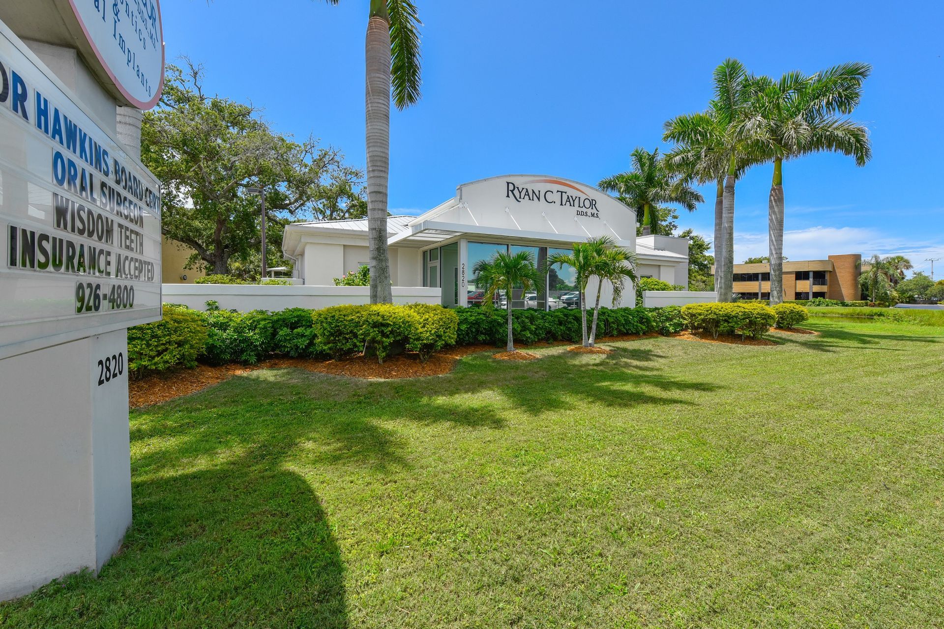 A large lawn with a building in the background and a sign in the foreground.