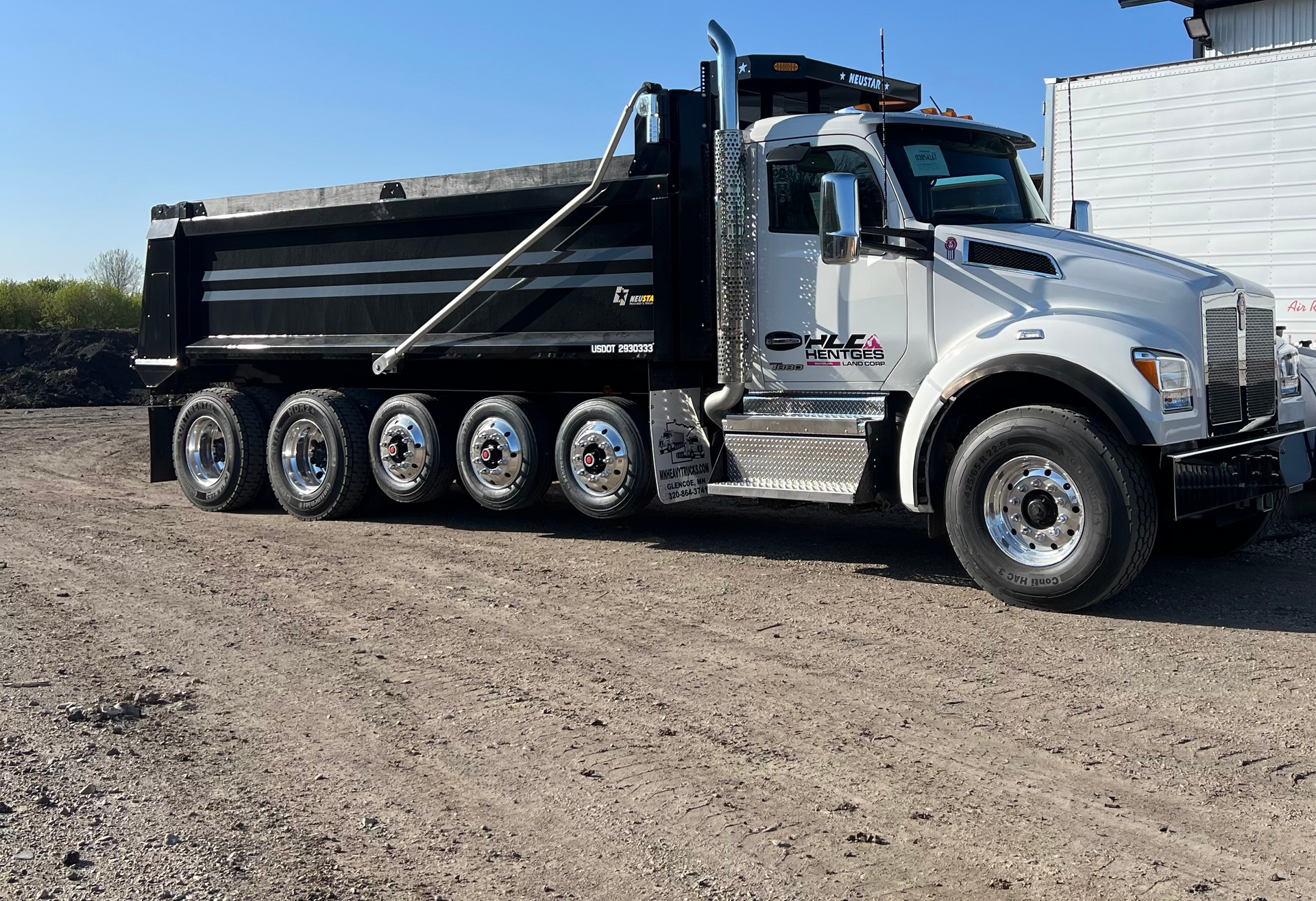 A dump truck is parked in a dirt lot.