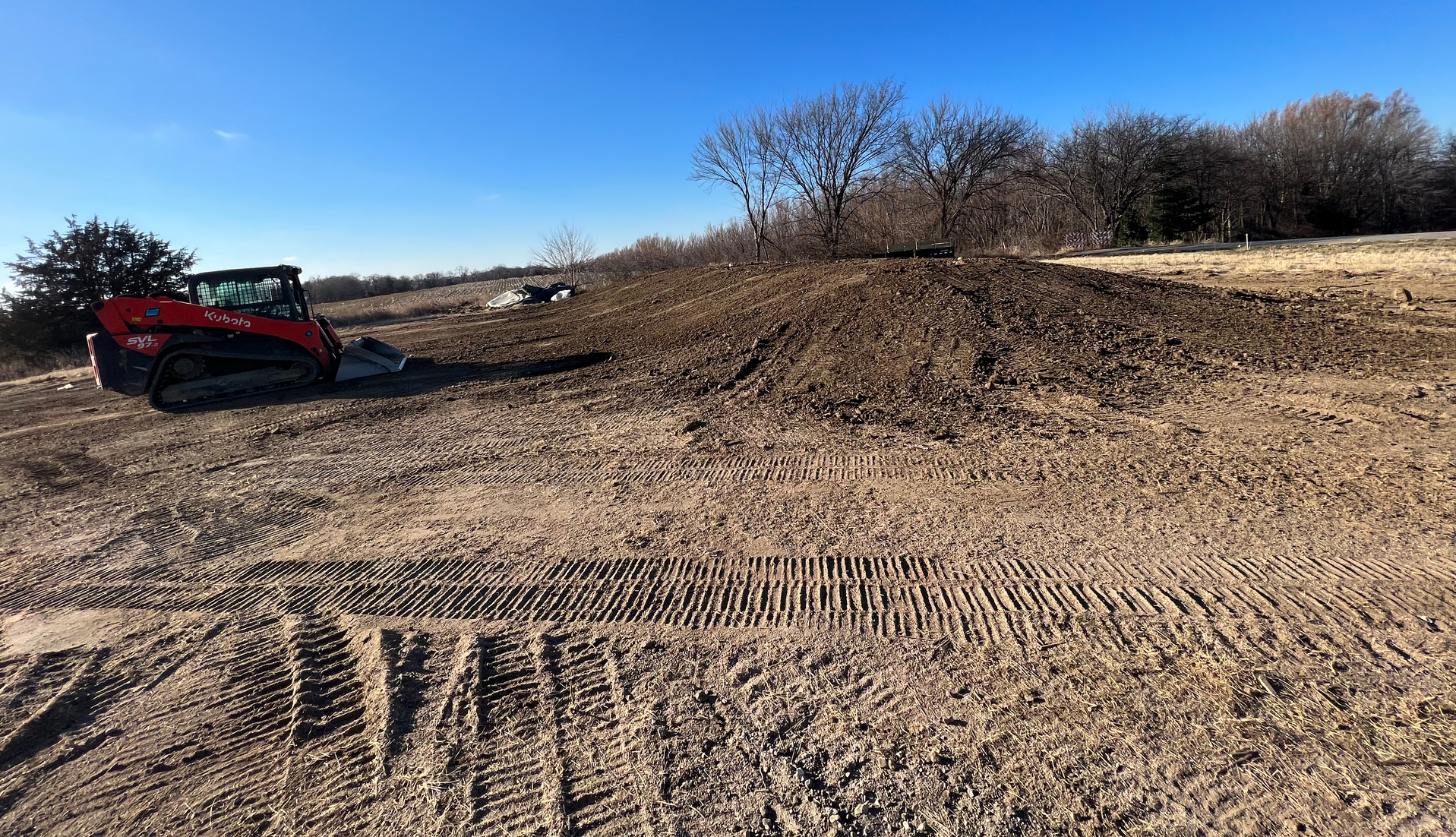 A red atv is parked in the middle of a dirt field.