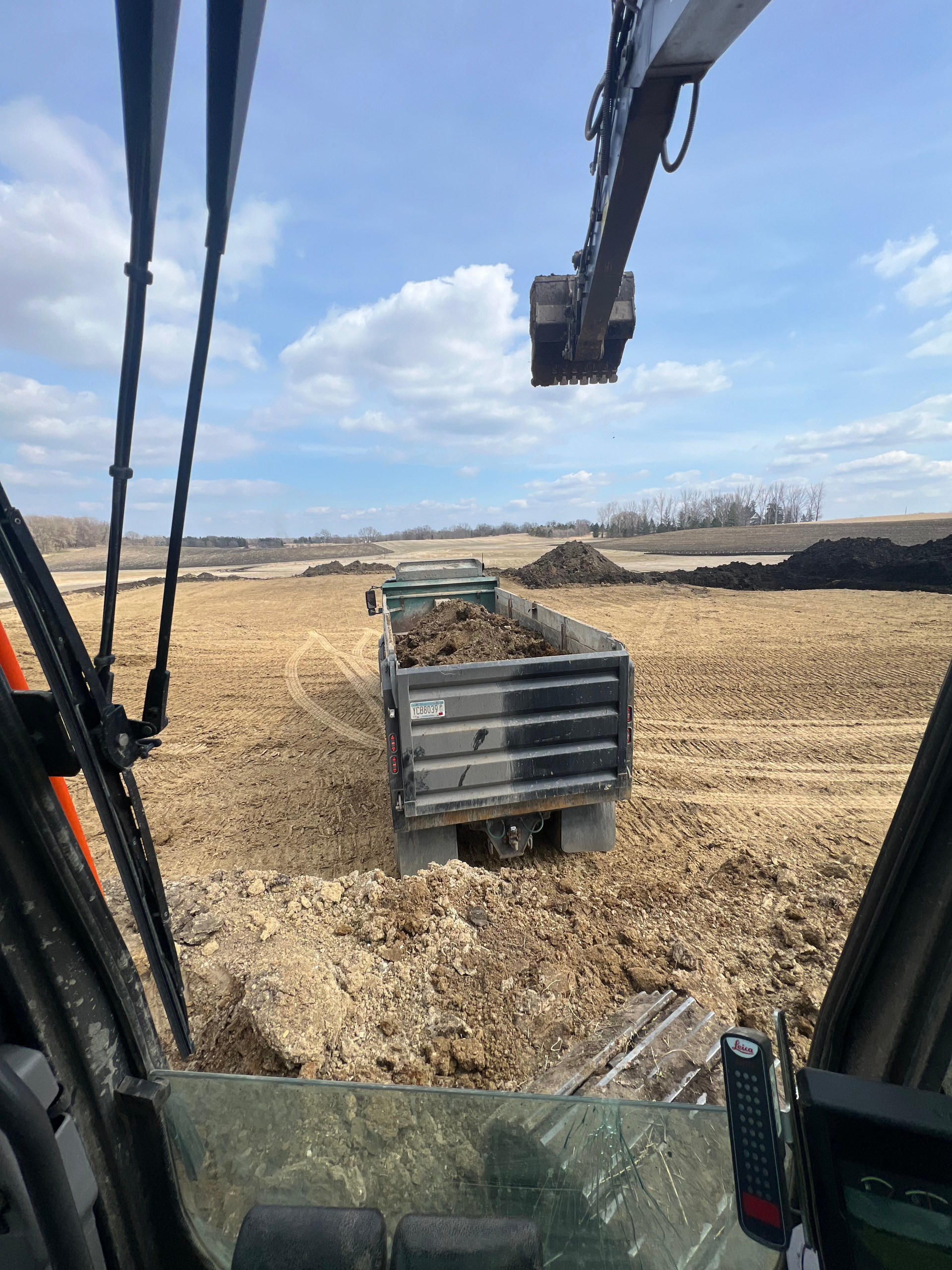 A truck is being loaded with dirt in a field.