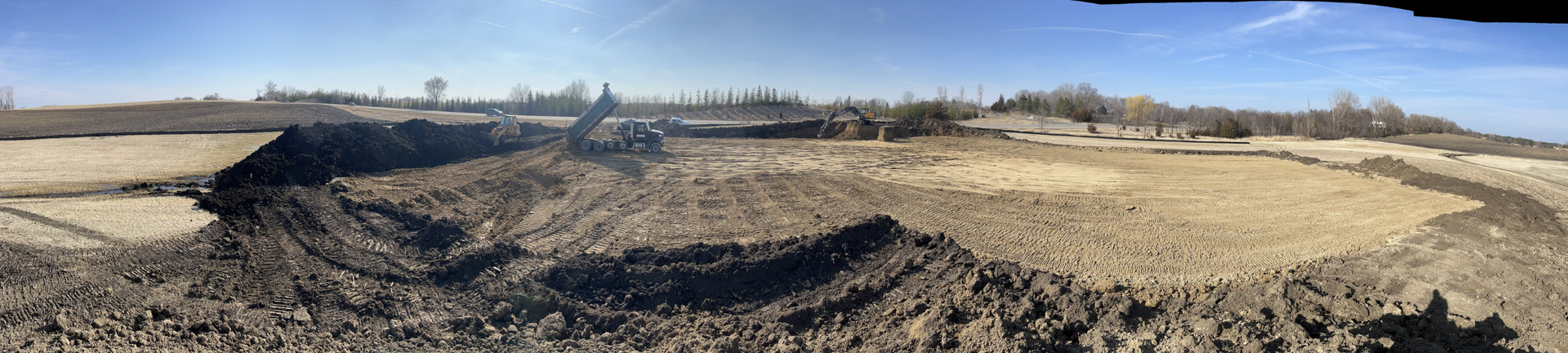 A tractor is plowing a field of dry grass on a sunny day.