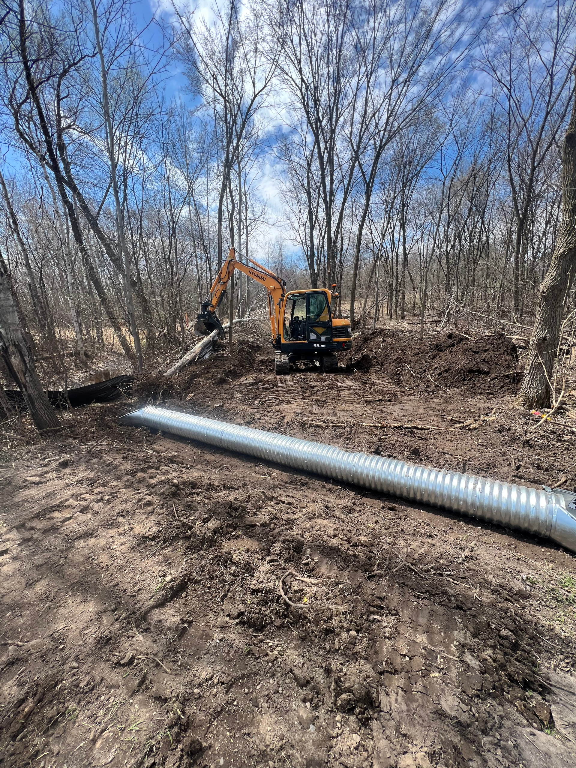 A large pipe is sitting in the middle of a dirt field.