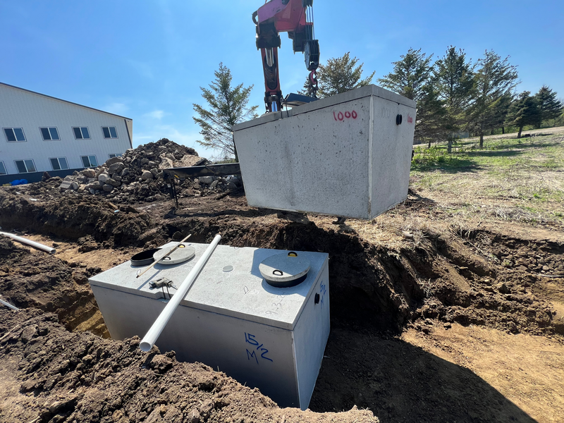 A crane is lifting a large concrete box into the ground.
