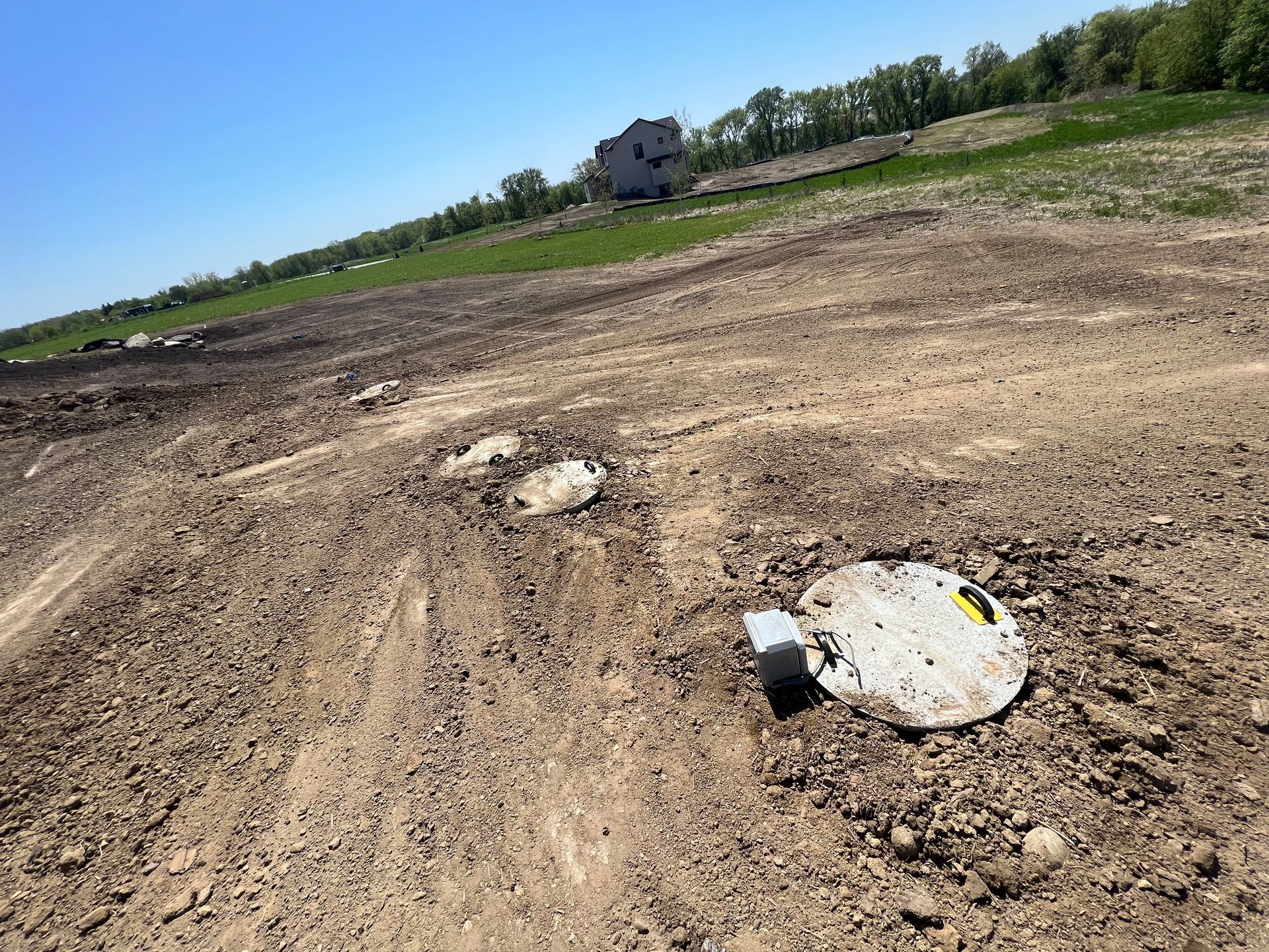 A manhole cover is sitting in the middle of a dirt field.