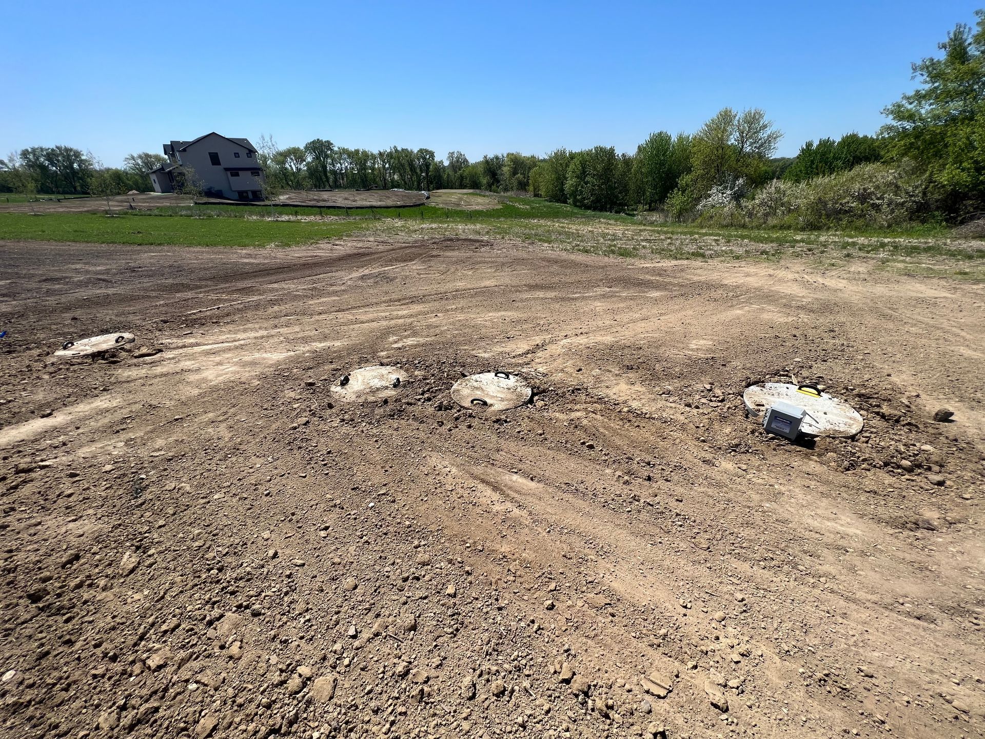 A dirt road going through a field with a building in the background.