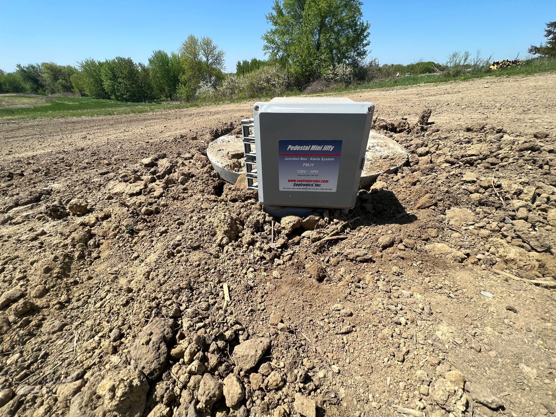 A box is sitting in the middle of a dirt field.
