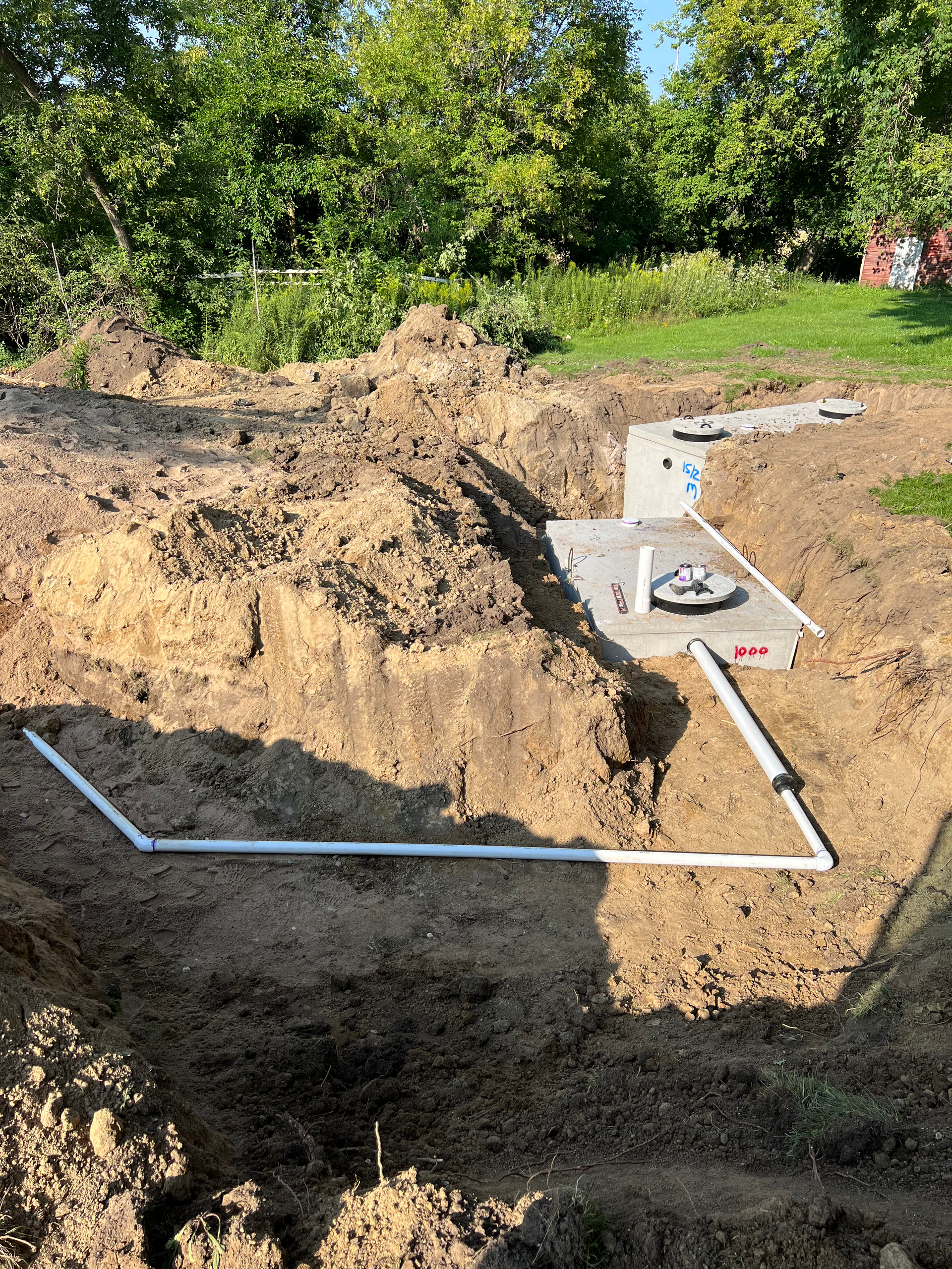A drainage system is being installed in the dirt in a backyard.