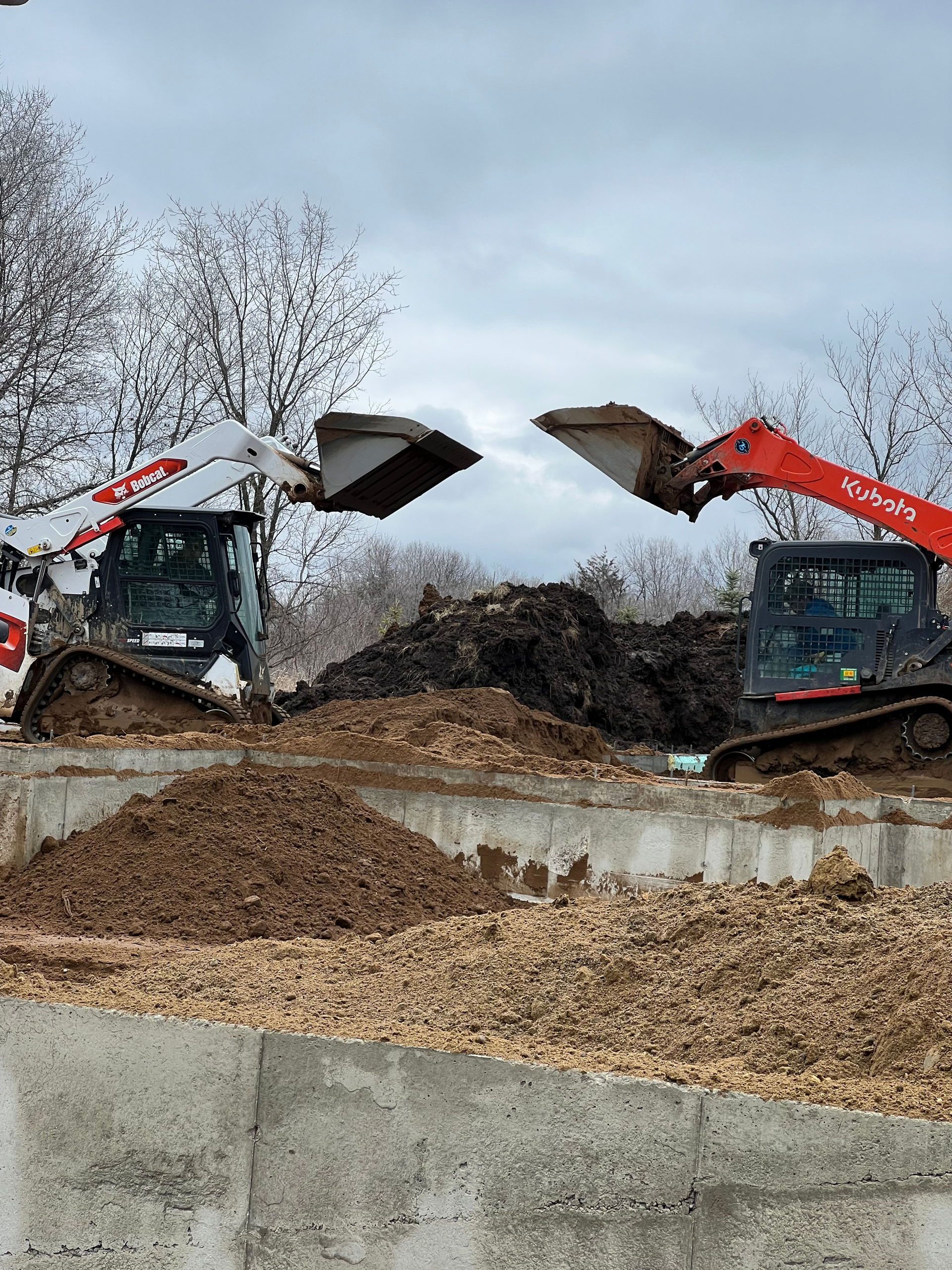 Two bulldozers are working on a construction site.