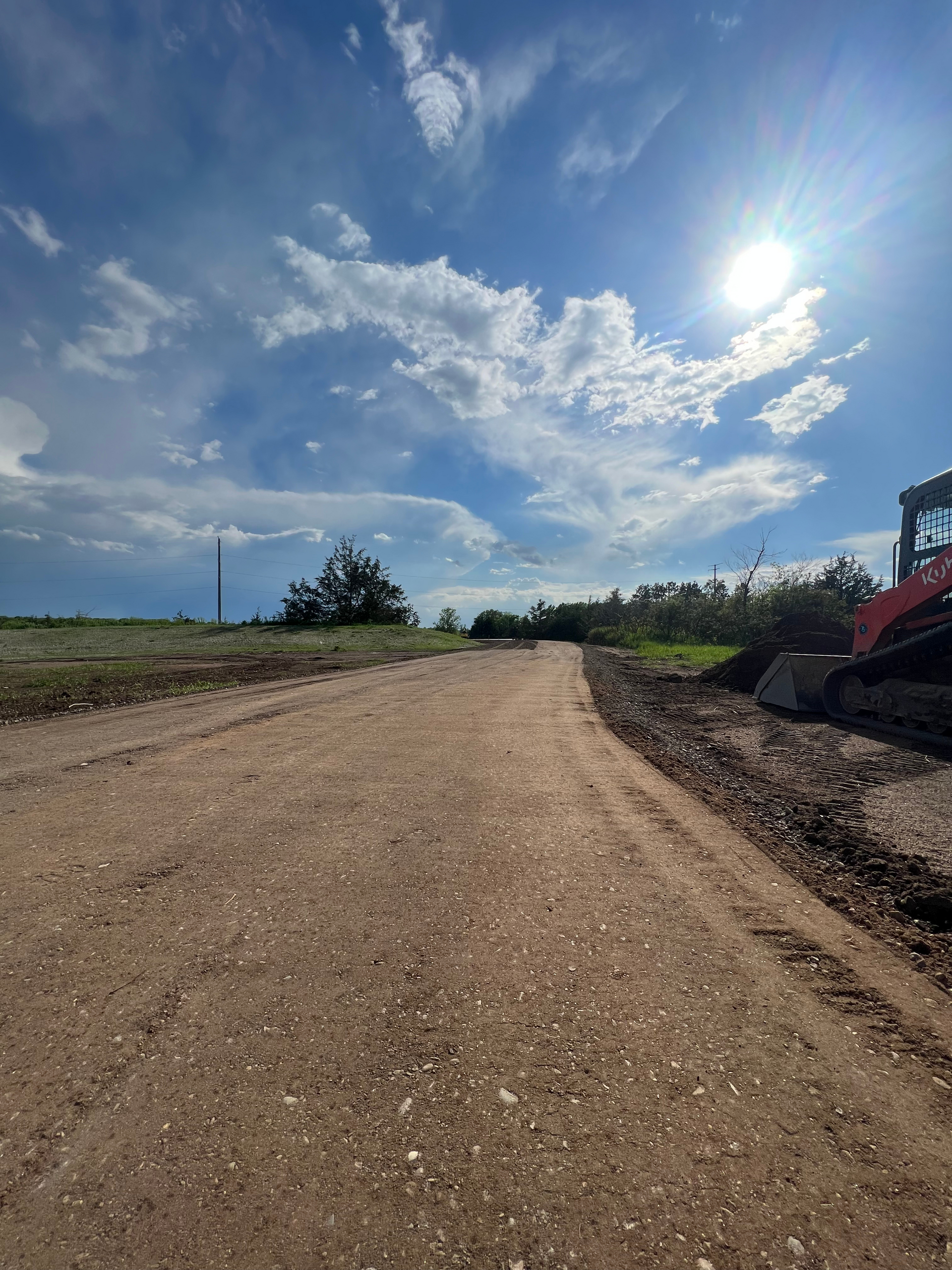 A dirt road with a bulldozer on the side of it.