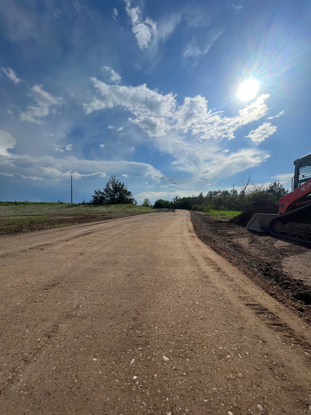 A dirt road with a bulldozer on the side of it.