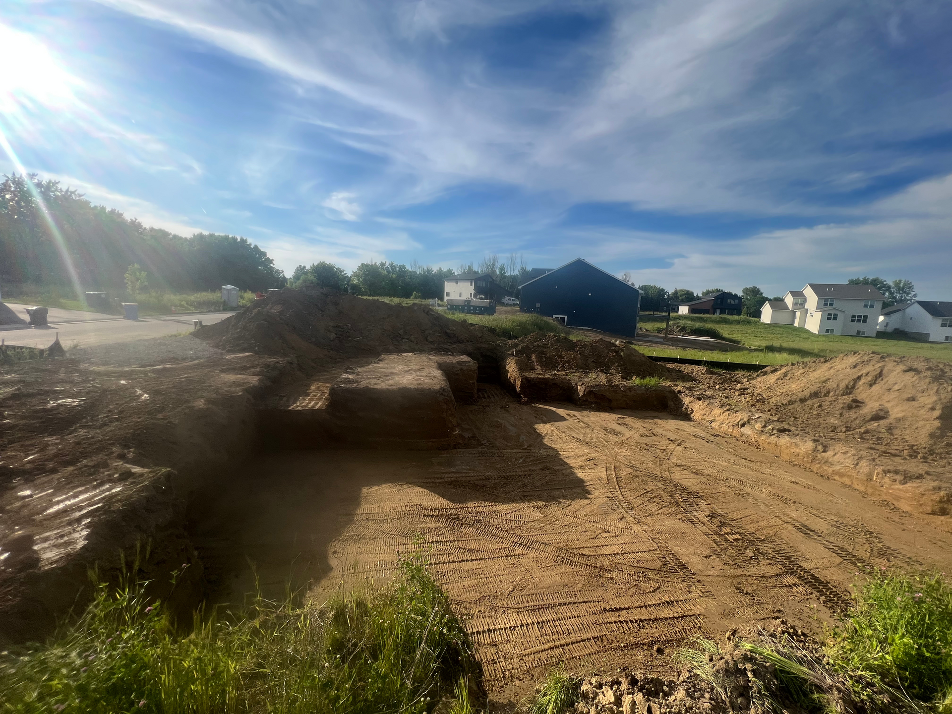 A construction site with a lot of dirt and houses in the background