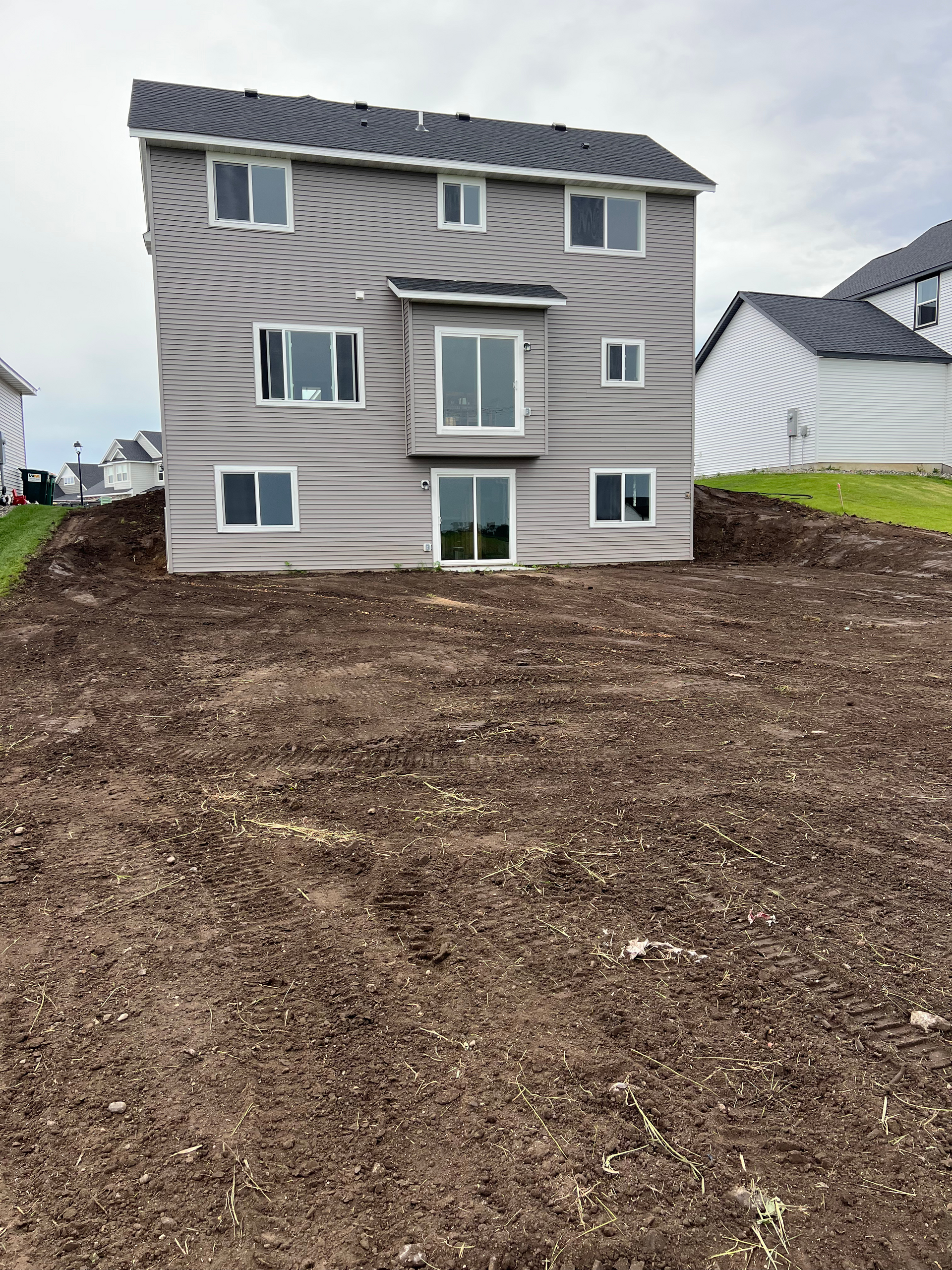 A large house is sitting on top of a dirt hill.