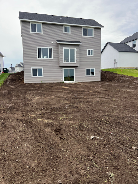 A large house is sitting on top of a dirt hill.
