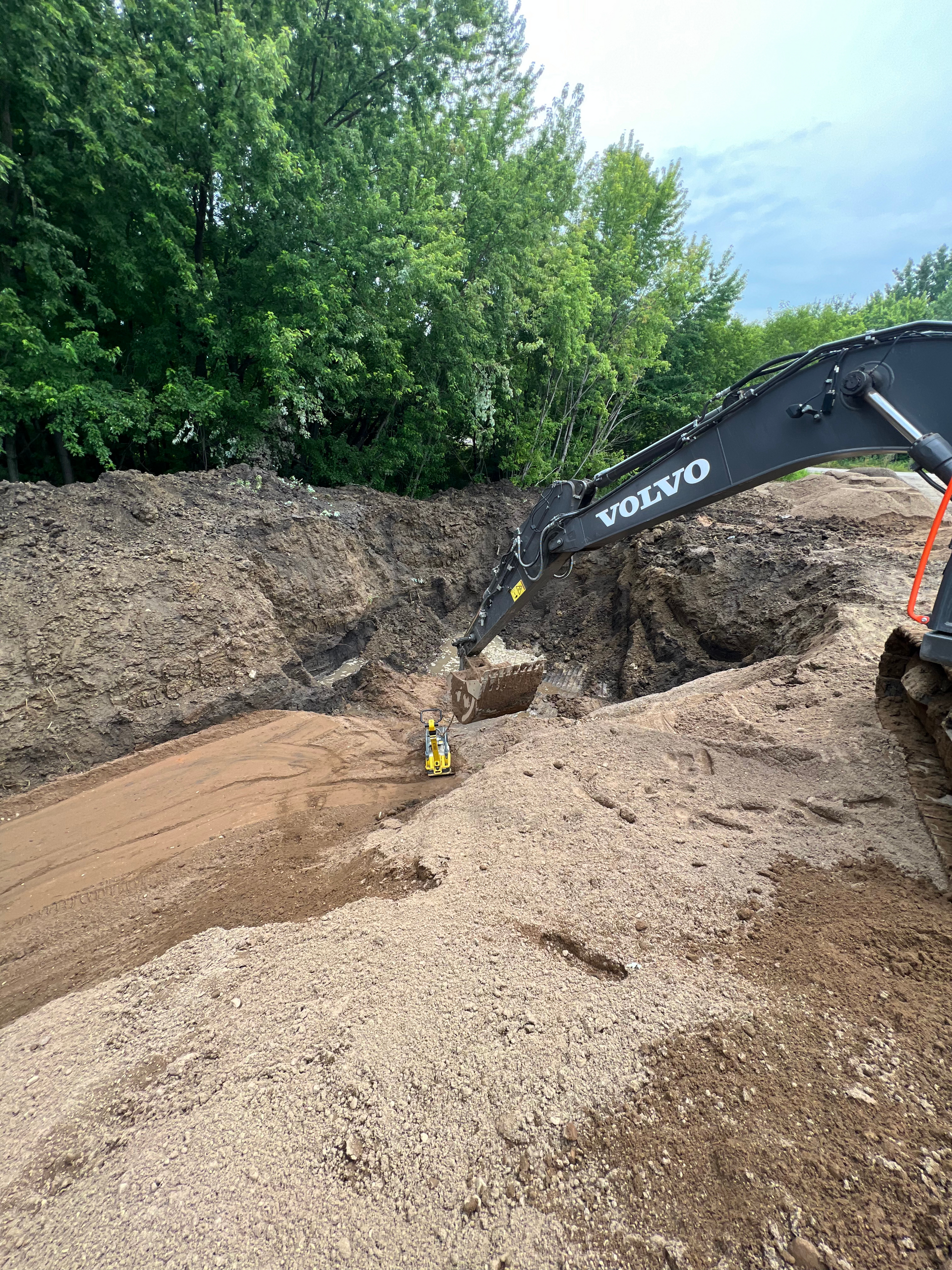 A volvo excavator is digging a hole in a pile of dirt.