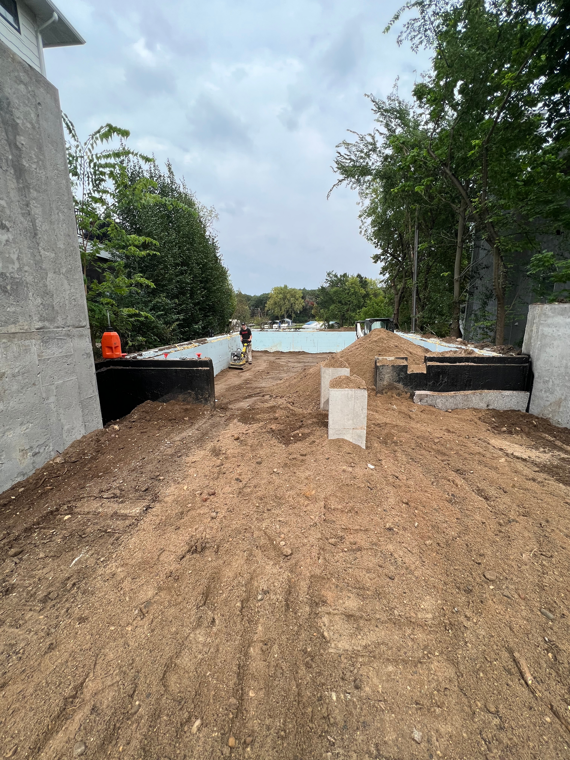 A dirt road leading to a pool with trees in the background.