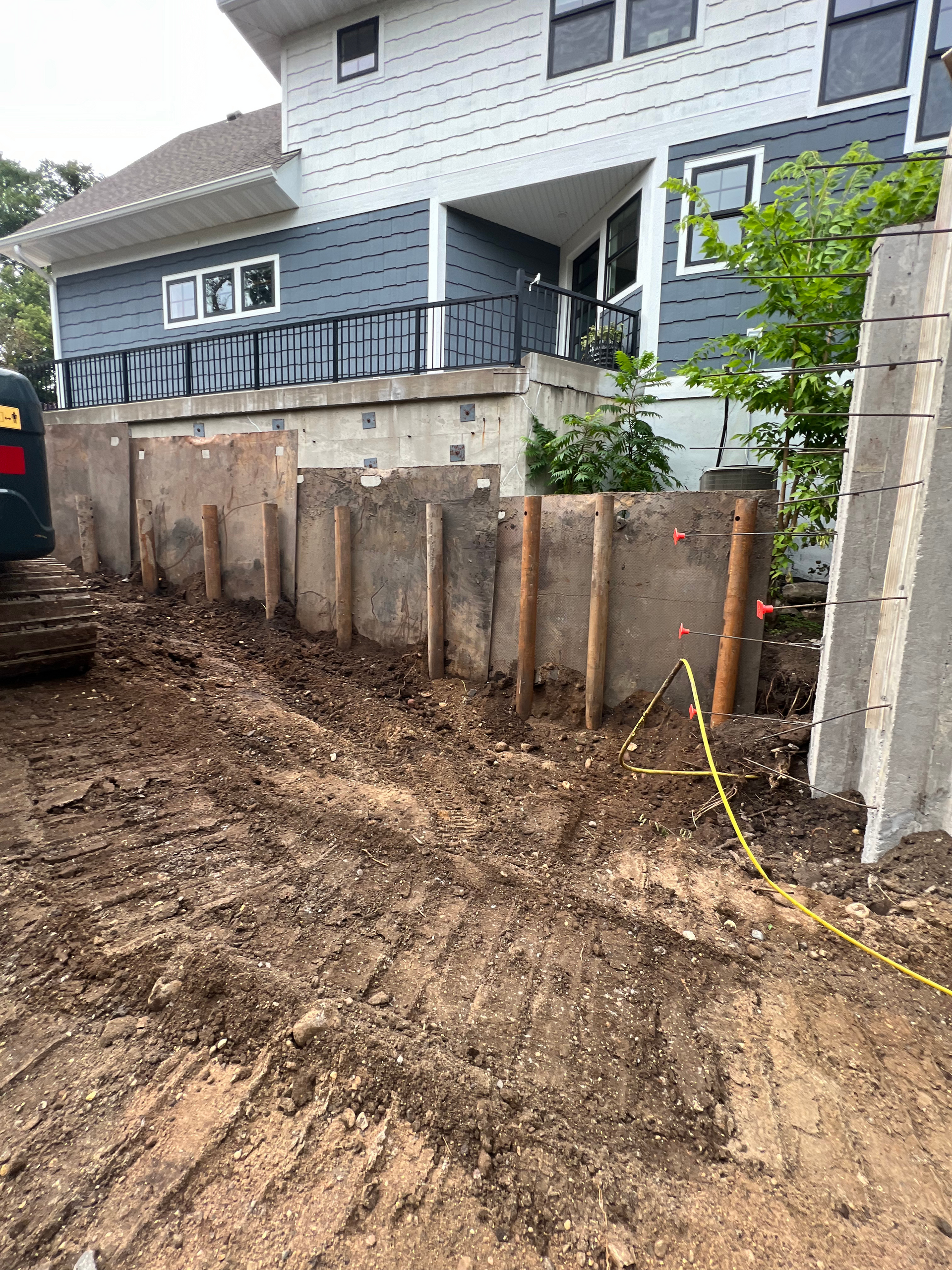 A construction site with a house in the background and a bulldozer in the foreground.