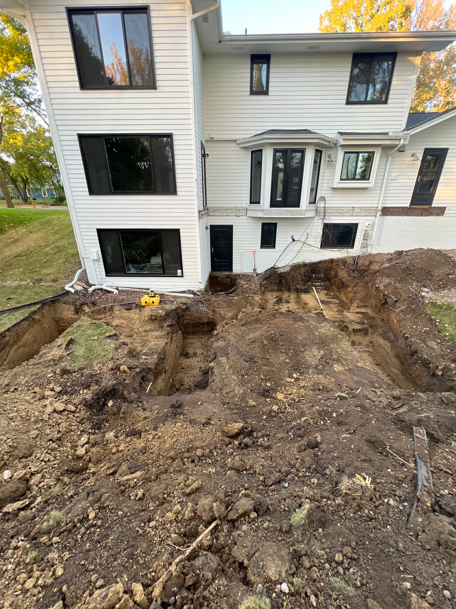 A white house with a large hole in the ground in front of it.