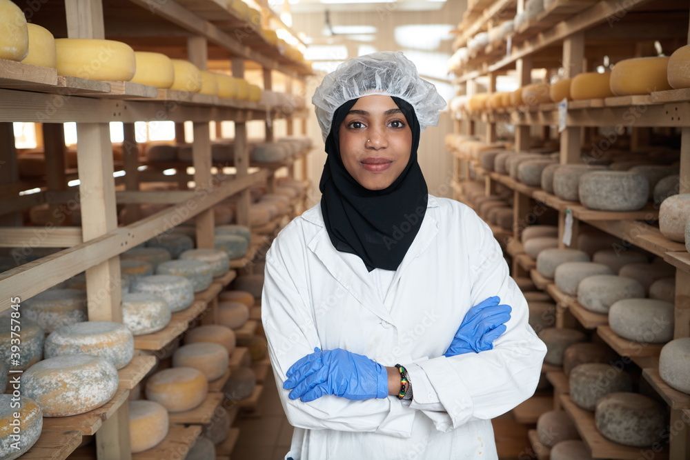 Cheese maker standing next to ageing cheese | Institute for Cheese & Dairy