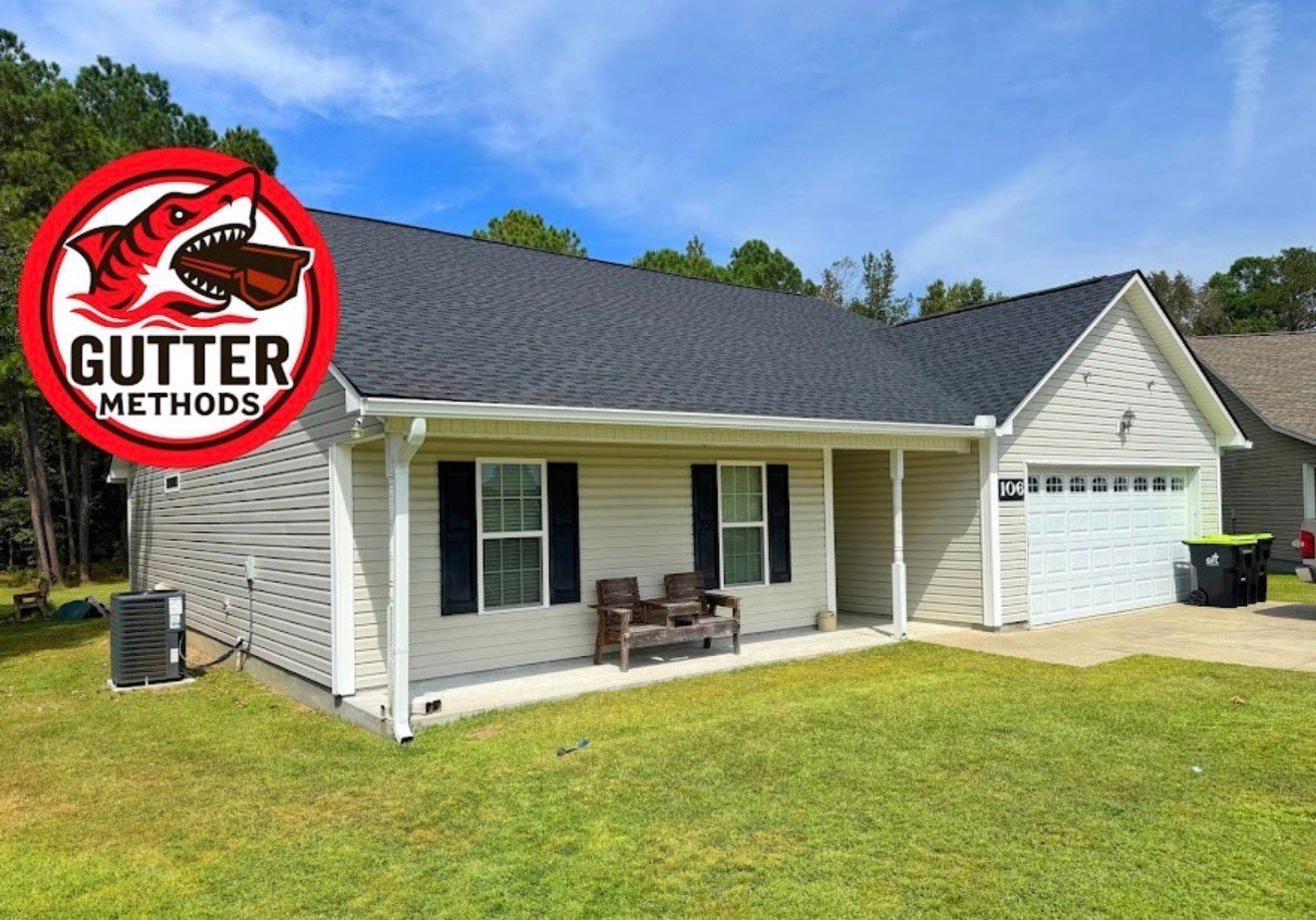 Two people on a scaffold in front of a brick building; one painting the trim, the other looking.
