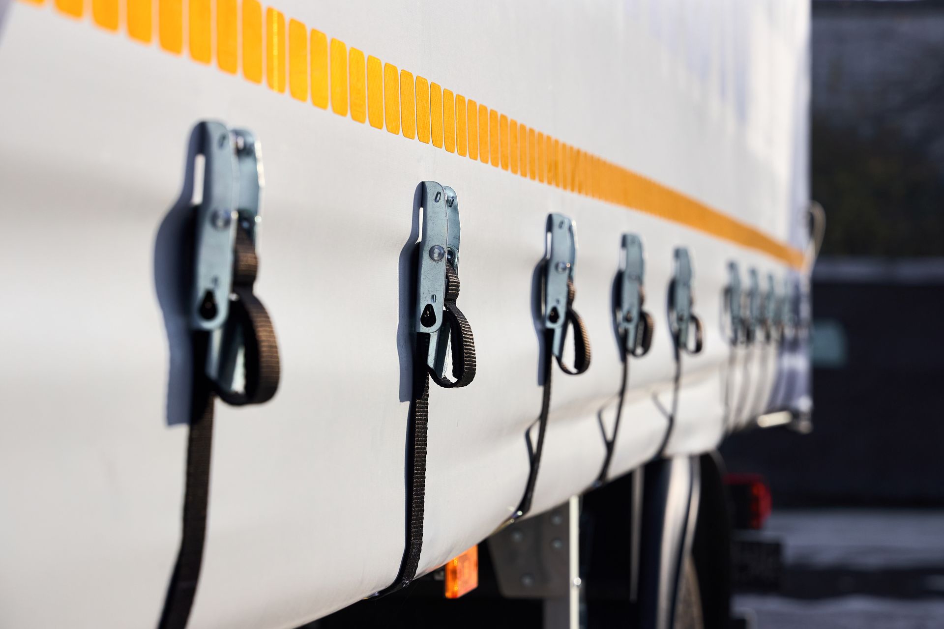 Custom industrial tarp systems secured with ratchet straps along the side of a commercial truck. Custom industrial tarp systems secured with ratchet straps along the side of a commercial truck.