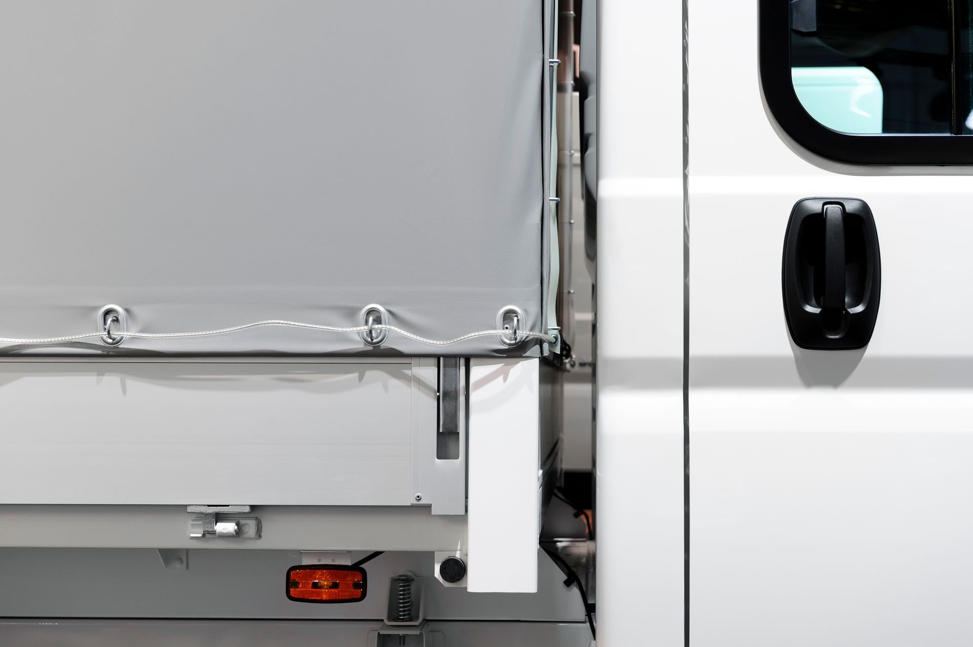 Commercial truck detail showcasing industrial tarp systems with white cab and gray cargo tarp. Commercial truck detail showcasing industrial tarp systems with white cab and gray cargo tarp.