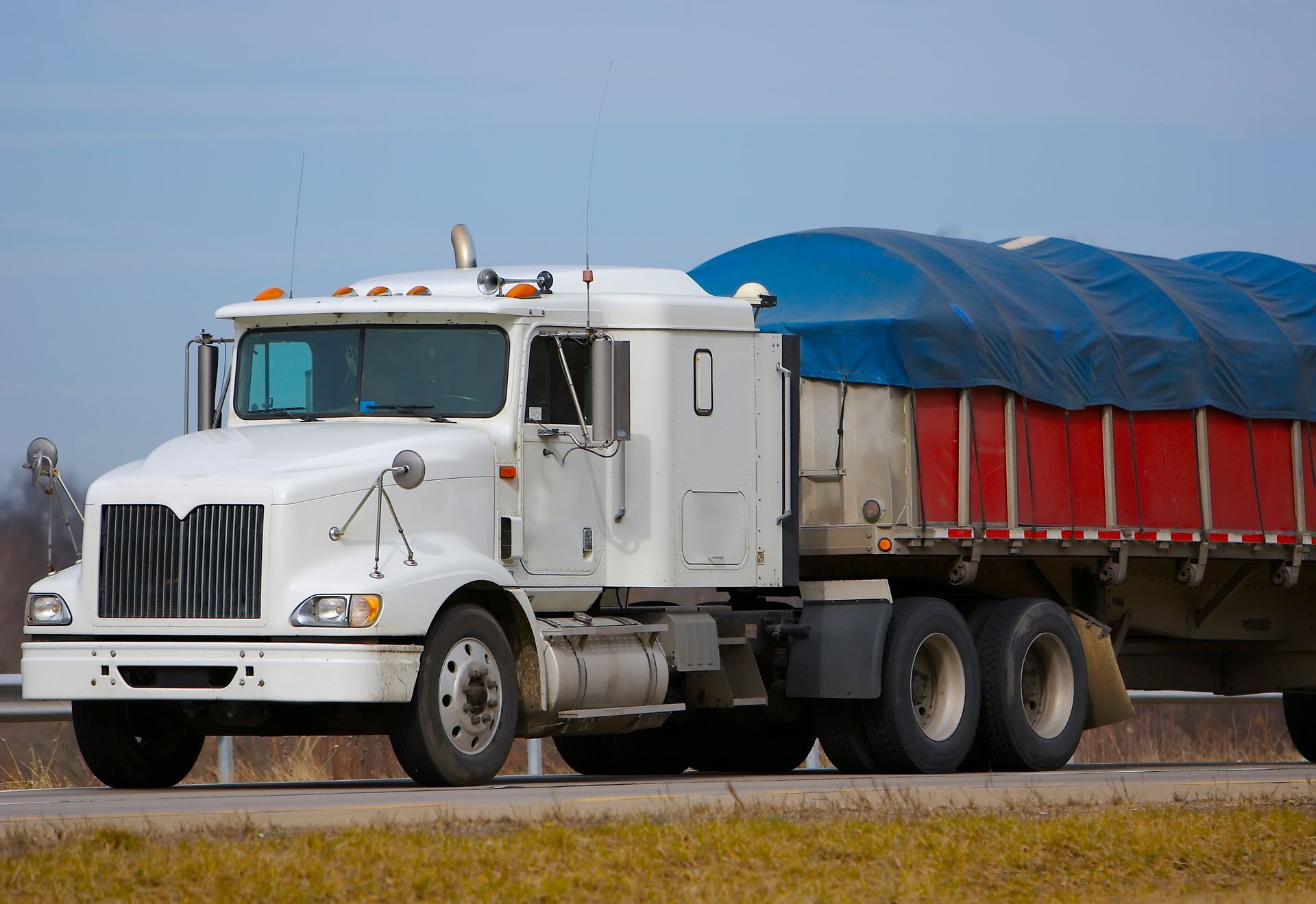 A tractor trailer with a canvas covering a load on its truck bed. A tractor trailer with a canvas covering a load on its truck bed.
