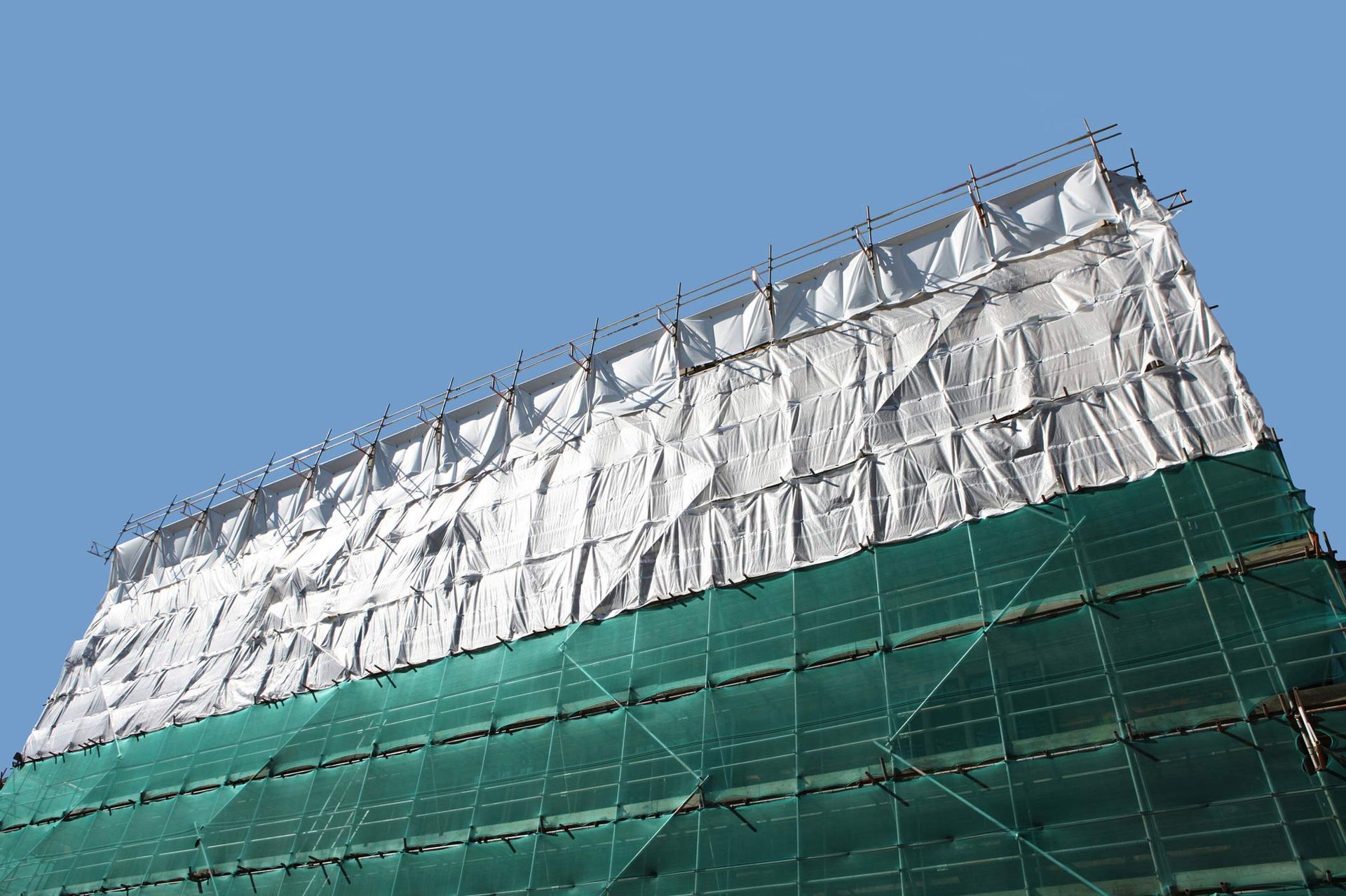 Protective industrial tarp cover and scaffolding on building restoration. Protective industrial tarp cover and scaffolding on building restoration.