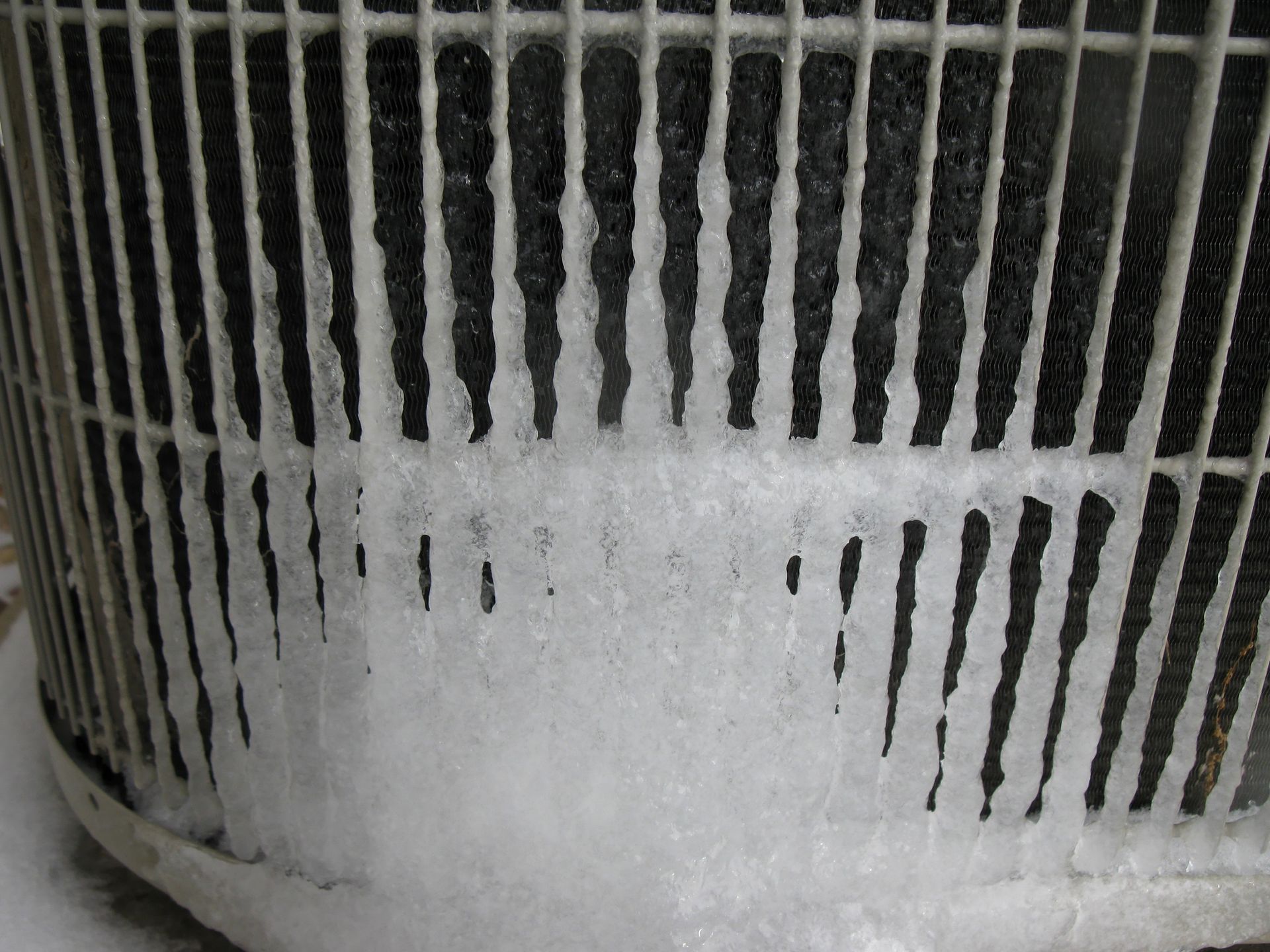 Close-up of an air conditioner unit that needs repair with visible ice buildup on the coils.