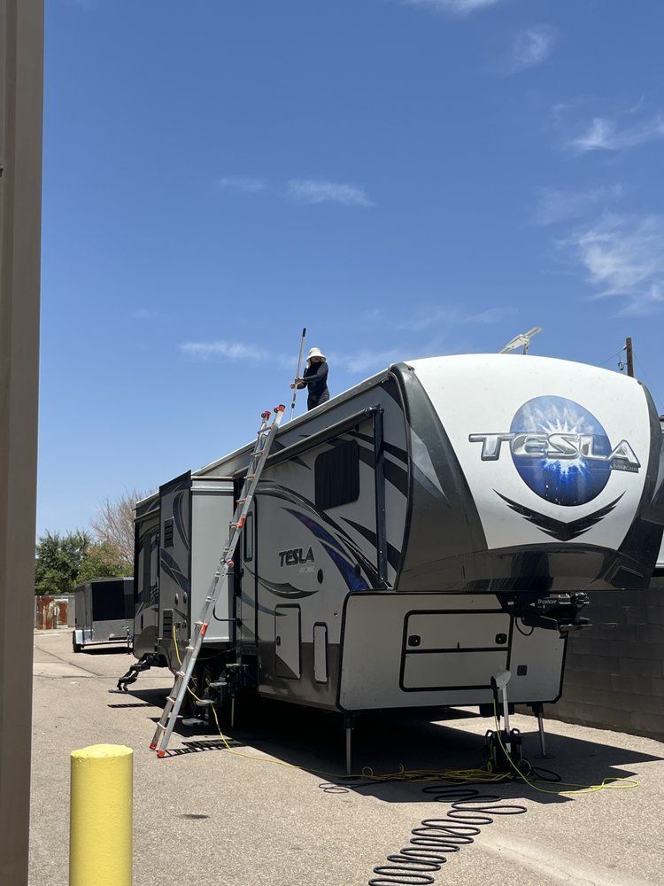 A man is standing on top of a rv in a parking lot.