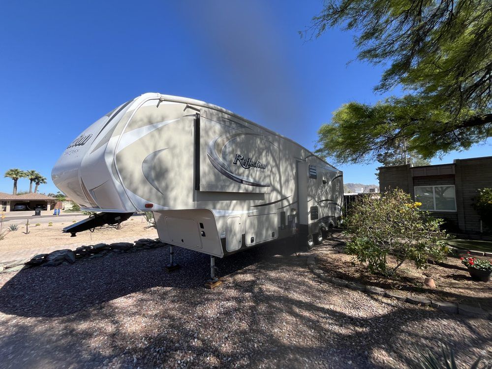 A large white trailer is parked in front of a house.